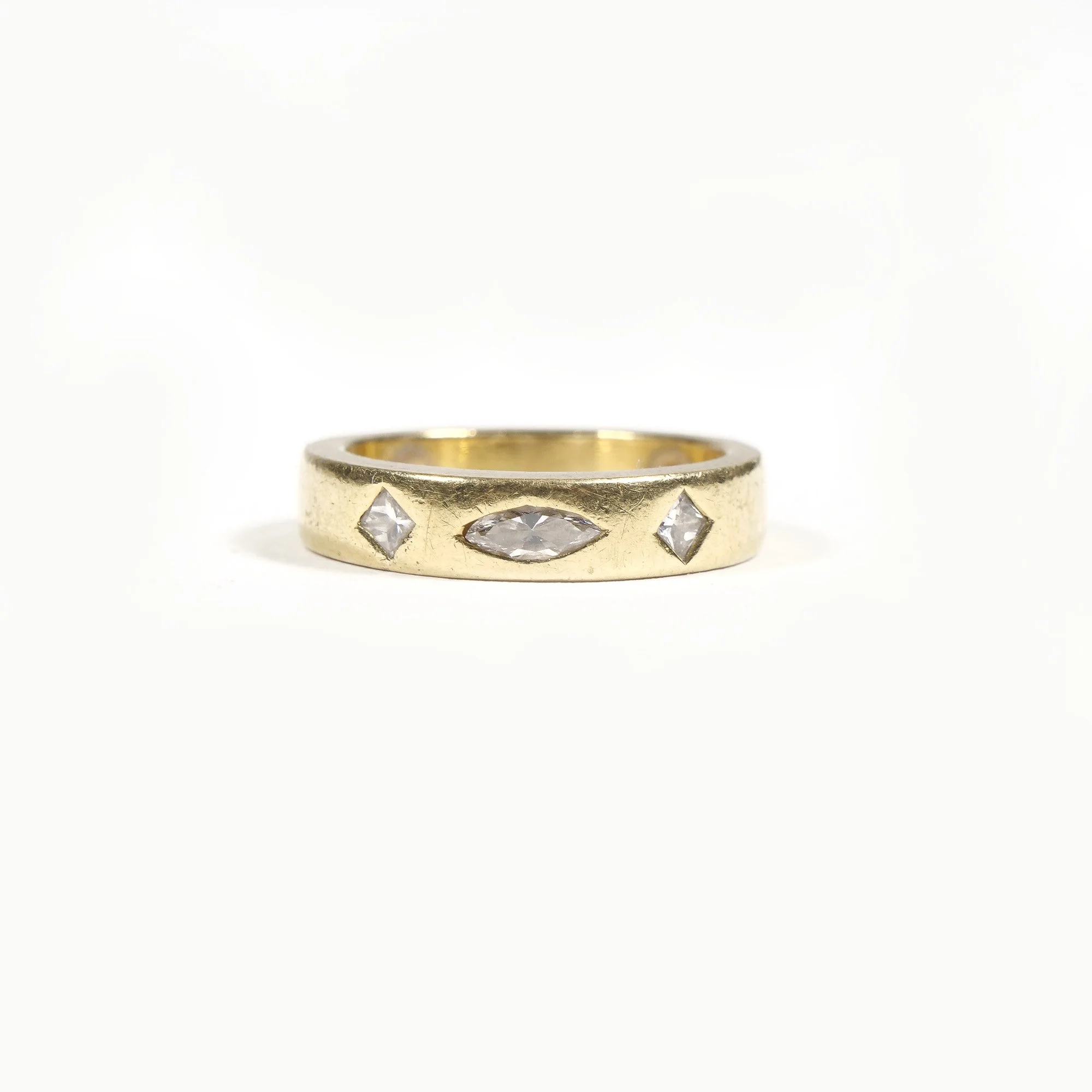 Gold ring with four clear gemstones, one marquise-shaped and three diamond-shaped, set into the band.