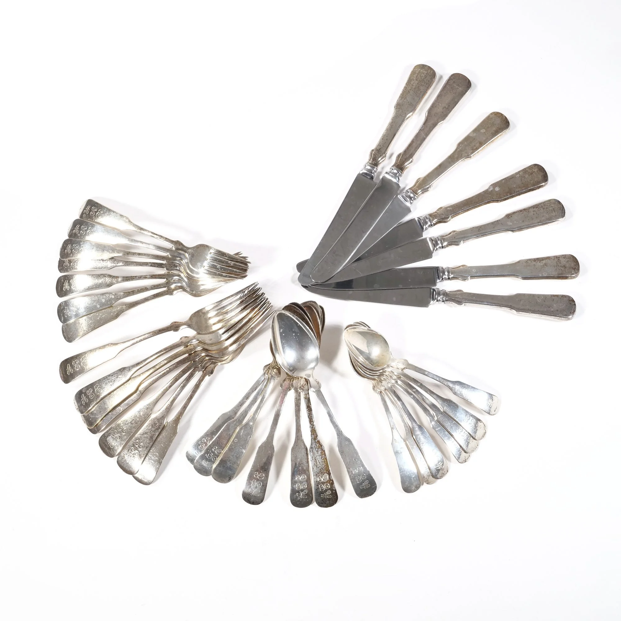 An arrangement of vintage silverware, including forks, knives, and spoons, on a white background, auctioned and photographed by ACES Gallery.