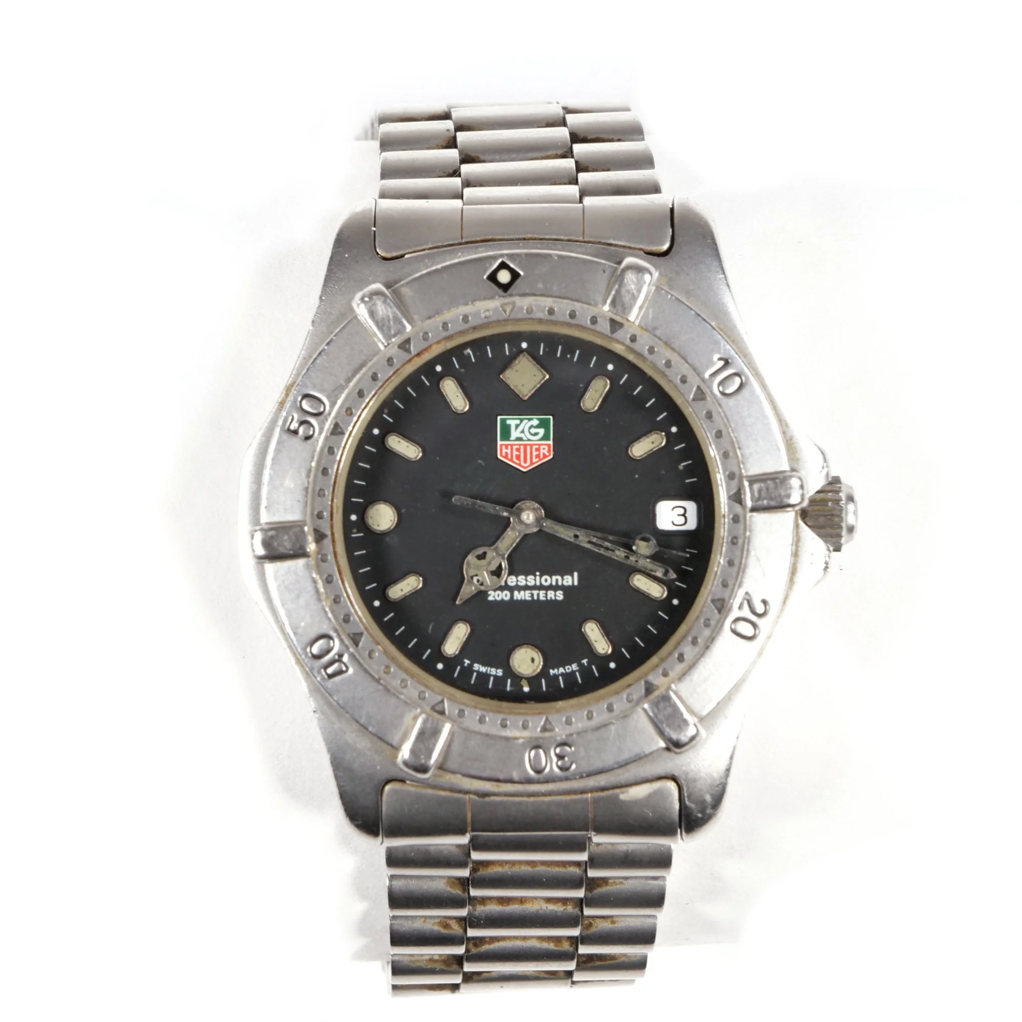 A vintage TAG Heuer Professional wristwatch with a black dial, silver bezel, and metal bracelet, displaying the time and date, auctioned and photographed by ACES Gallery.