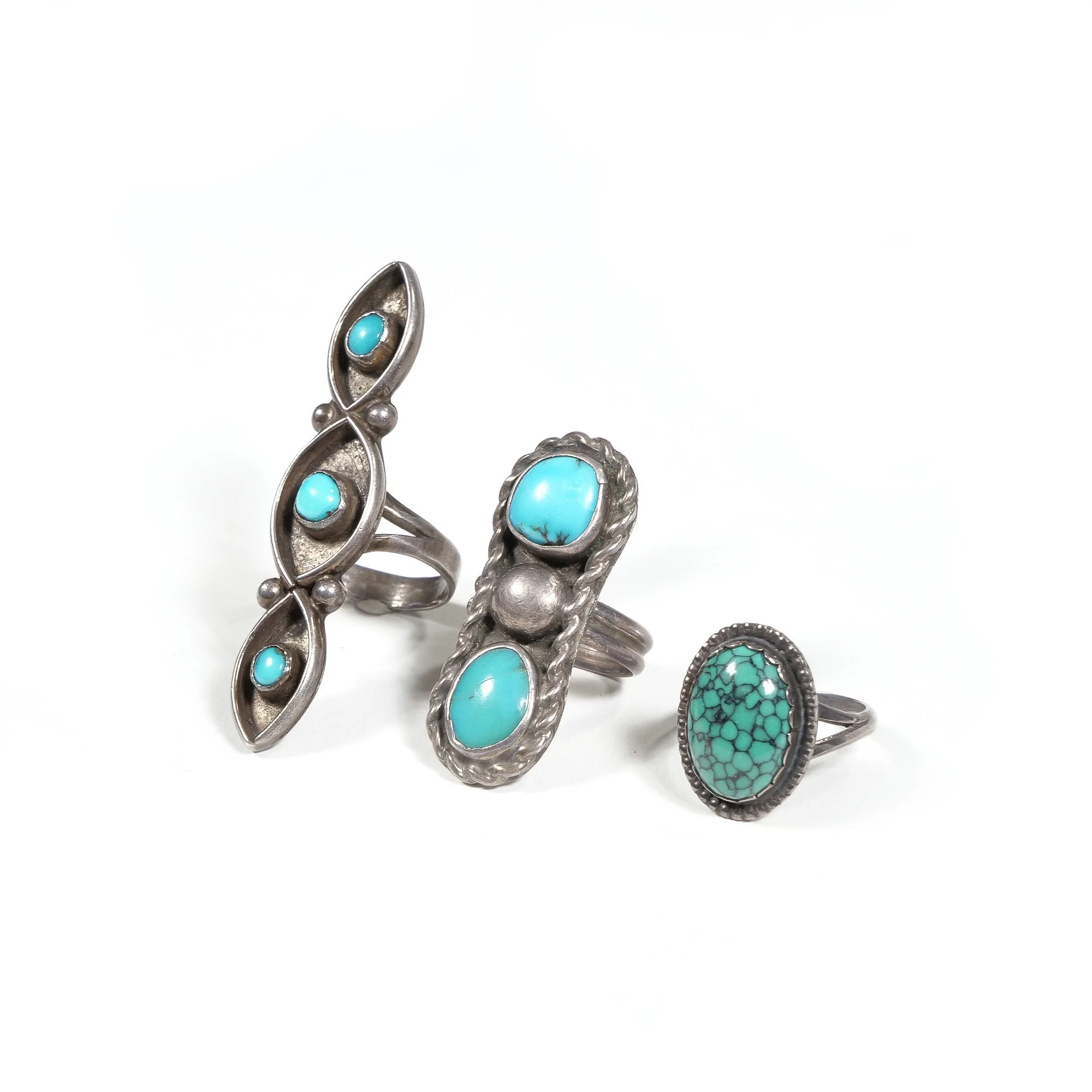 Three silver rings with turquoise stones on a white background, auctioned and photographed by ACES Gallery.