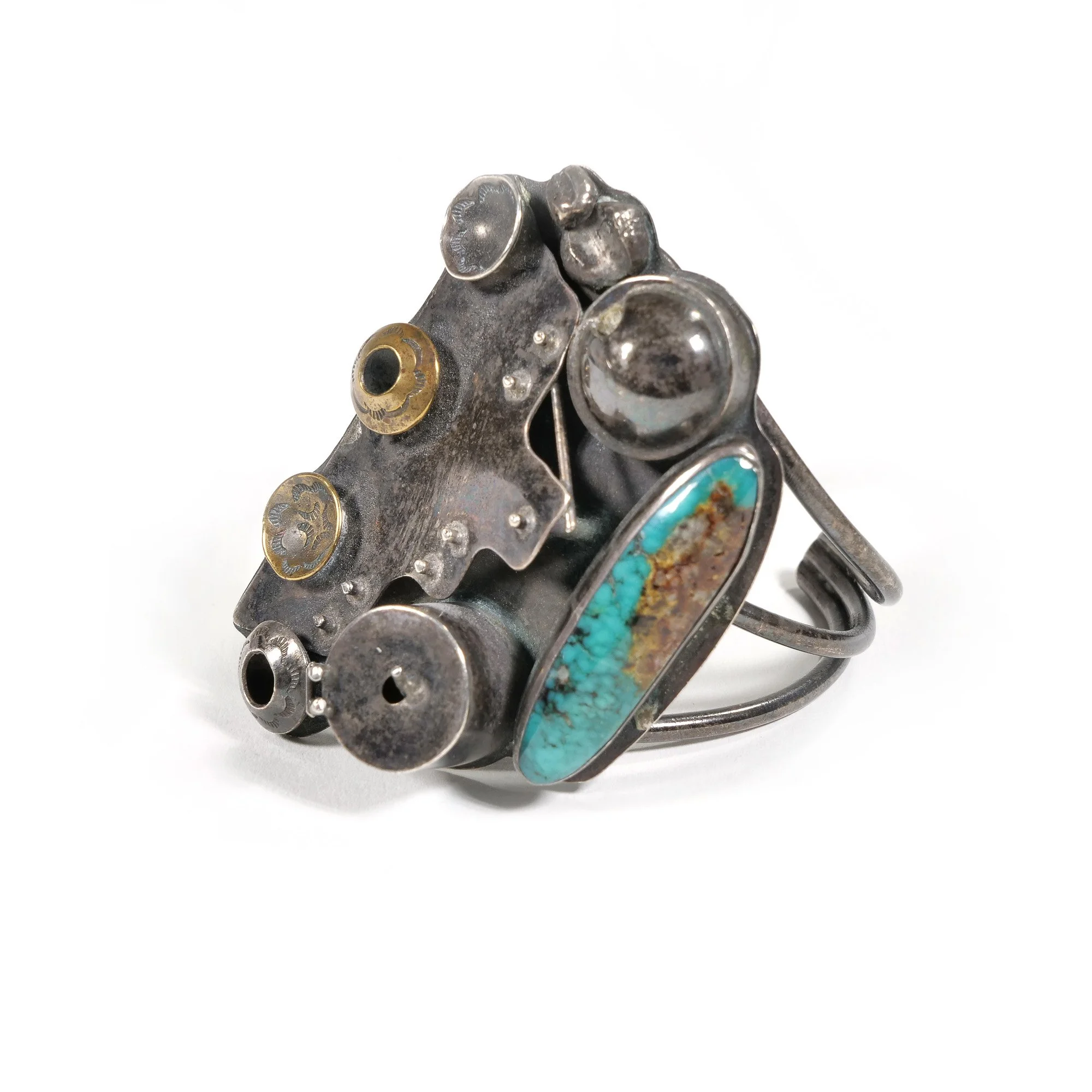 Silver ring with turquoise and rust stone, surrounded by metal gear and hardware components, on a white background, auctioned and photographed by ACES Gallery.