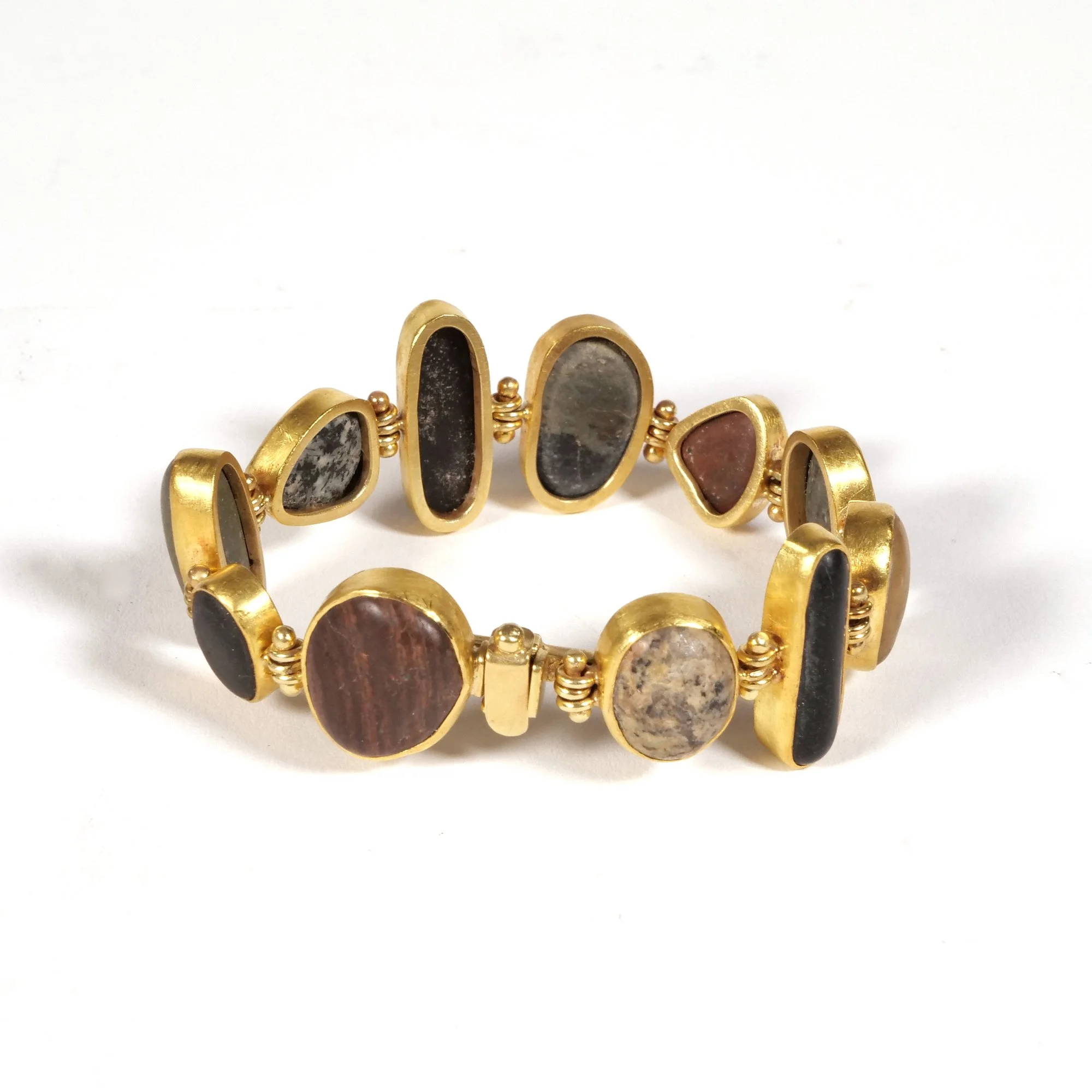 Gold bracelet with oval and irregularly shaped stones in black, pink, and patterned colors, auctioned and photographed by ACES Gallery.