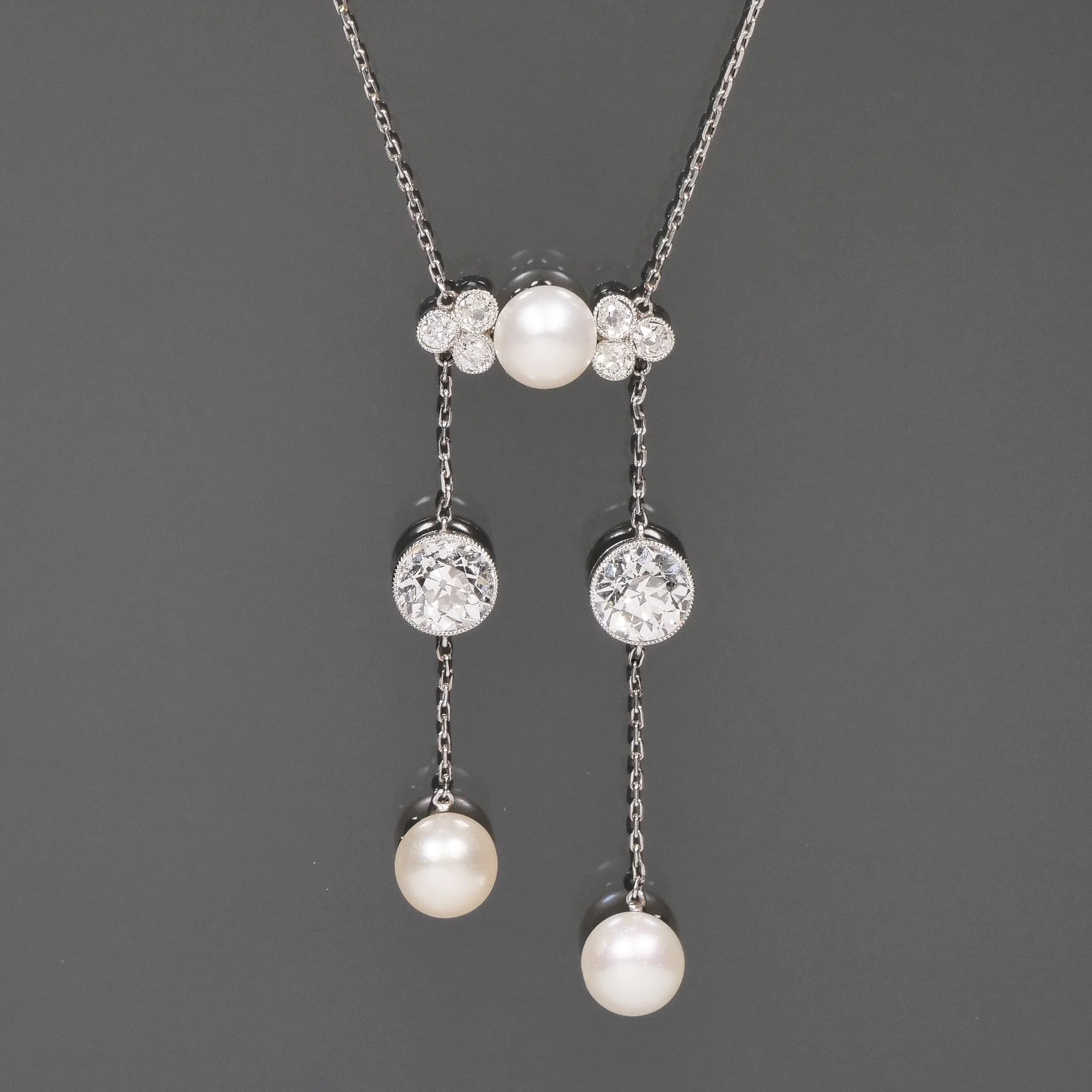 An art deco white gold necklace with pearls and diamonds, featuring a central pearl and two dangling pearls with diamonds, auctioned and photographed by ACES Gallery.