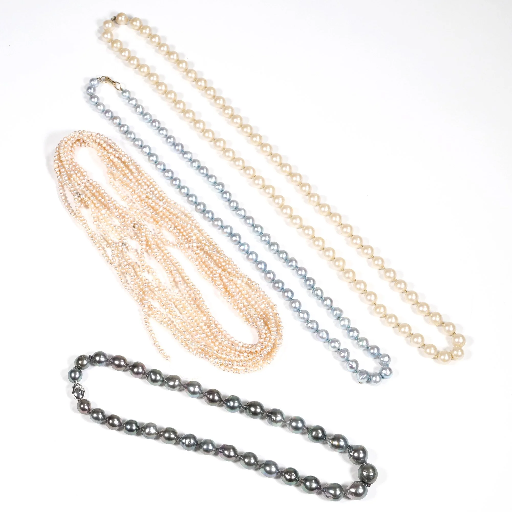 Assorted pearl necklaces in various colors including cream, silver, peach, and black displayed on a white background, auctioned and photographed by ACES Gallery.