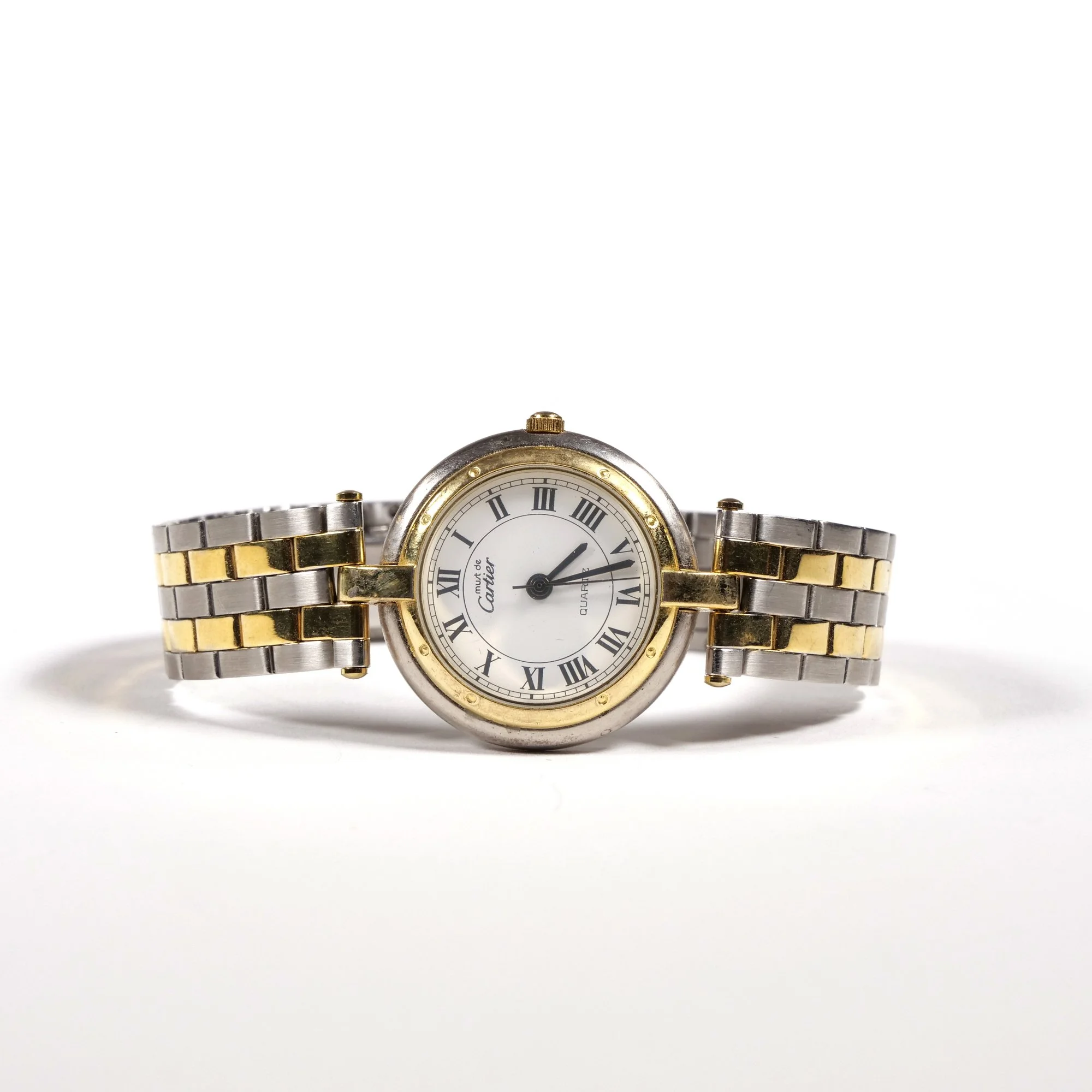 A wristwatch with a round face, Roman numeral hour markers, and a two-tone metal band with silver and gold links, placed on a white surface, auctioned and photographed by ACES Gallery.