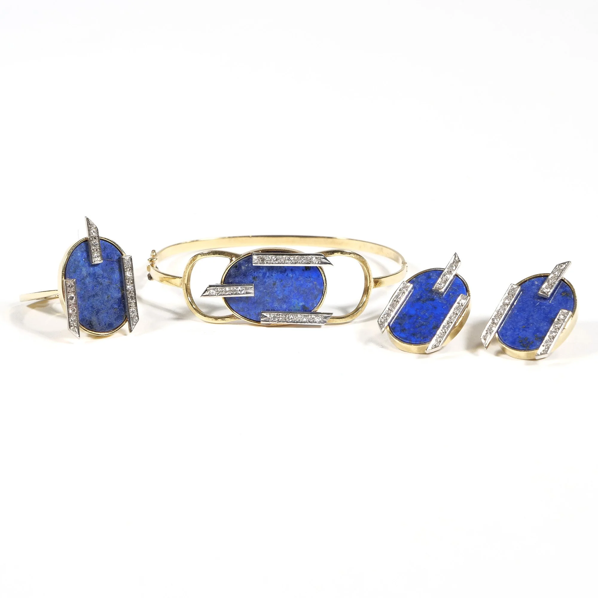 A jewelry set consisting of a ring, bracelet, and earrings, each featuring oval-shaped blue stones with silver and gold accents, and embedded with small diamonds, auctioned and photographed by ACES Gallery.