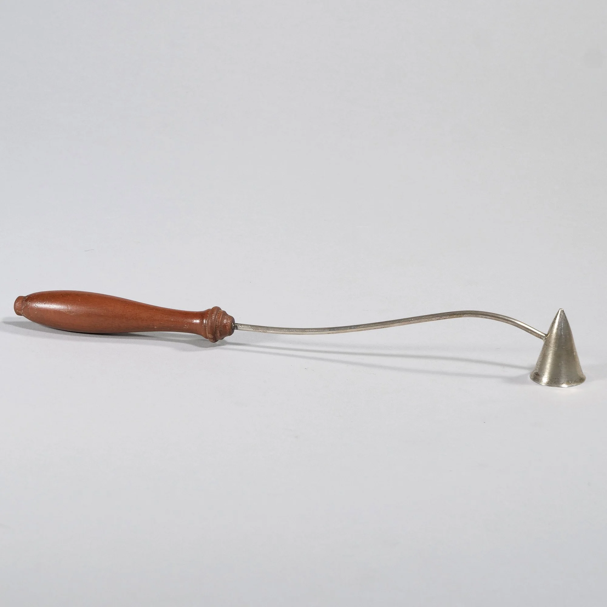 A sterling candle snuffer with a wooden handle on a plain white background, auctioned and photographed by ACES Gallery.