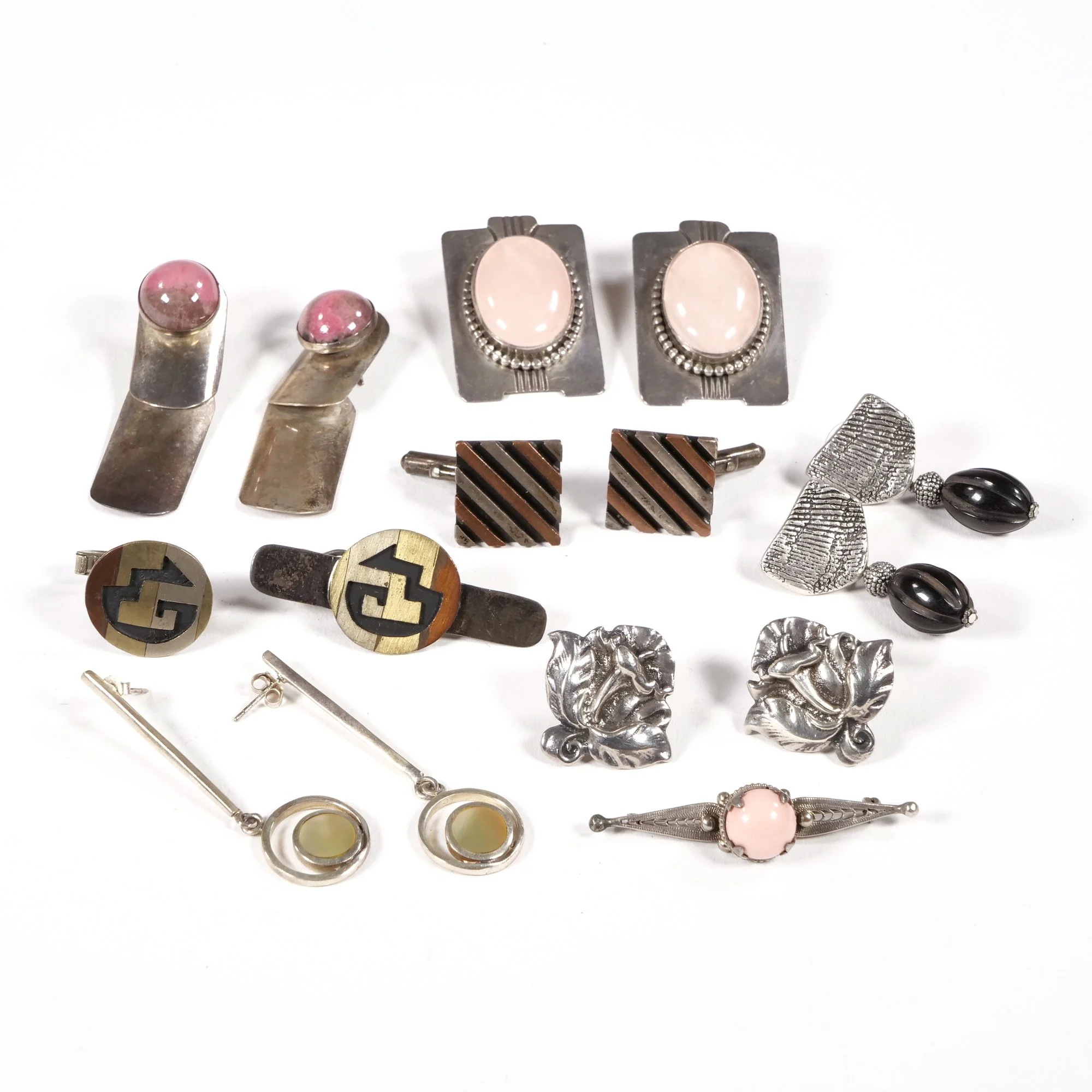 Assorted vintage jewelry including rings, earrings, and clips in various styles and materials displayed on a white background, auctioned and photographed by ACES Gallery.