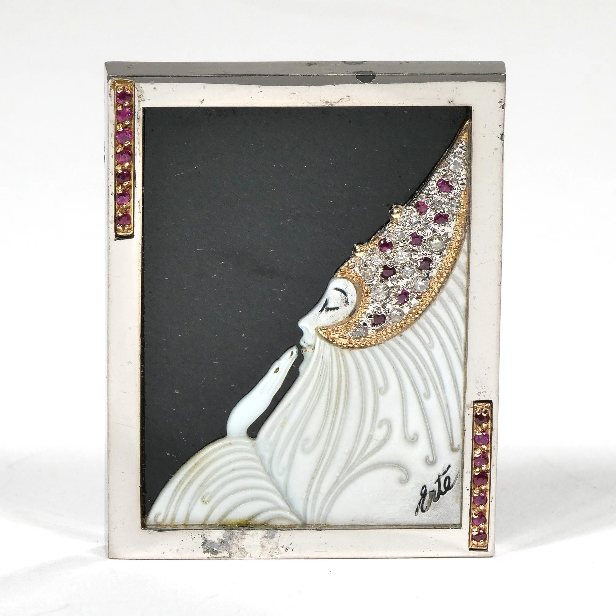 Decorative metal frame with a woman in profile blowing a kiss, adorned with pink and clear gemstones, signed 'Erte' near the bottom right, auctioned and photographed by ACES Gallery.