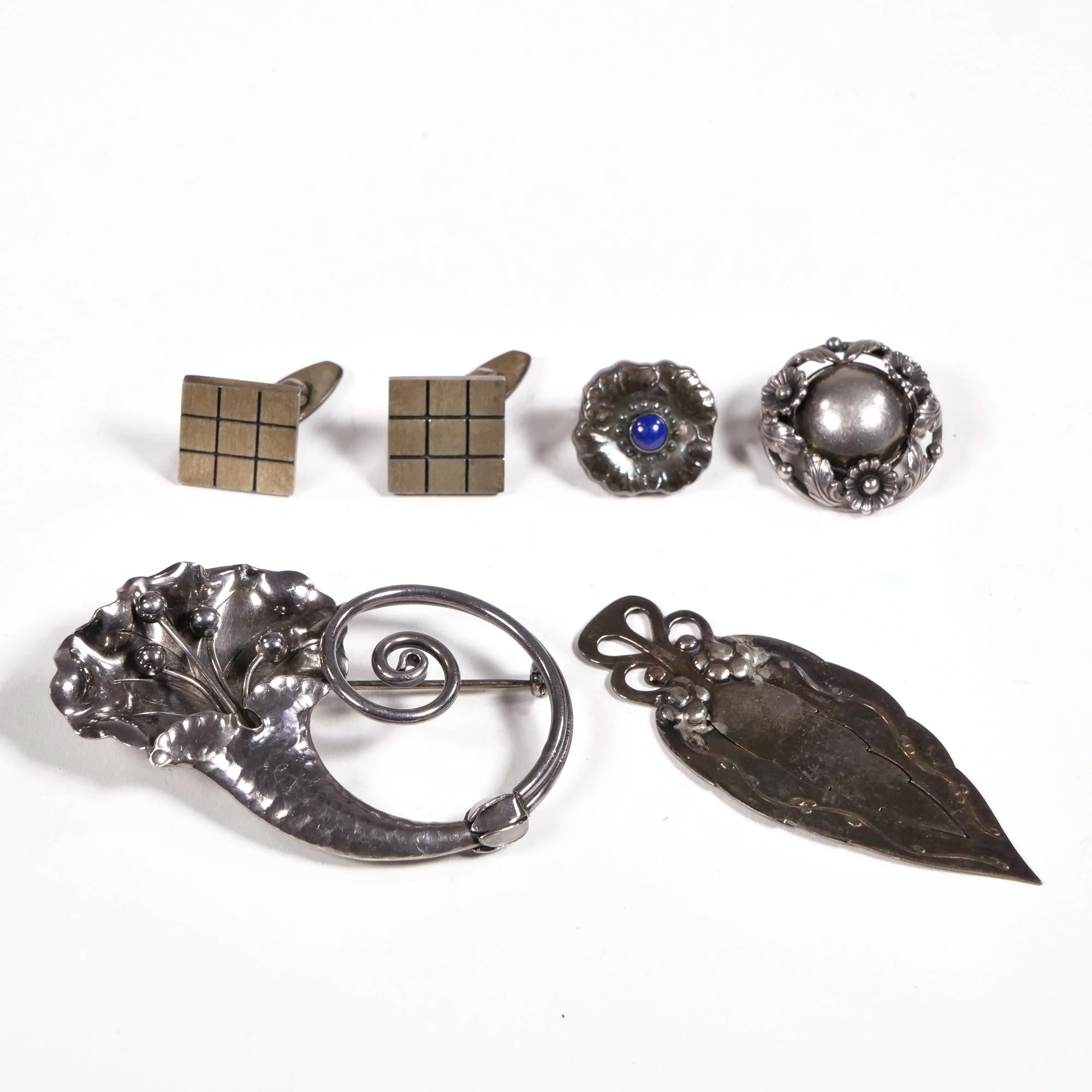 Collection of vintage silver jewelry including brooches and earrings with intricate designs, auctioned and photographed by ACES Gallery.