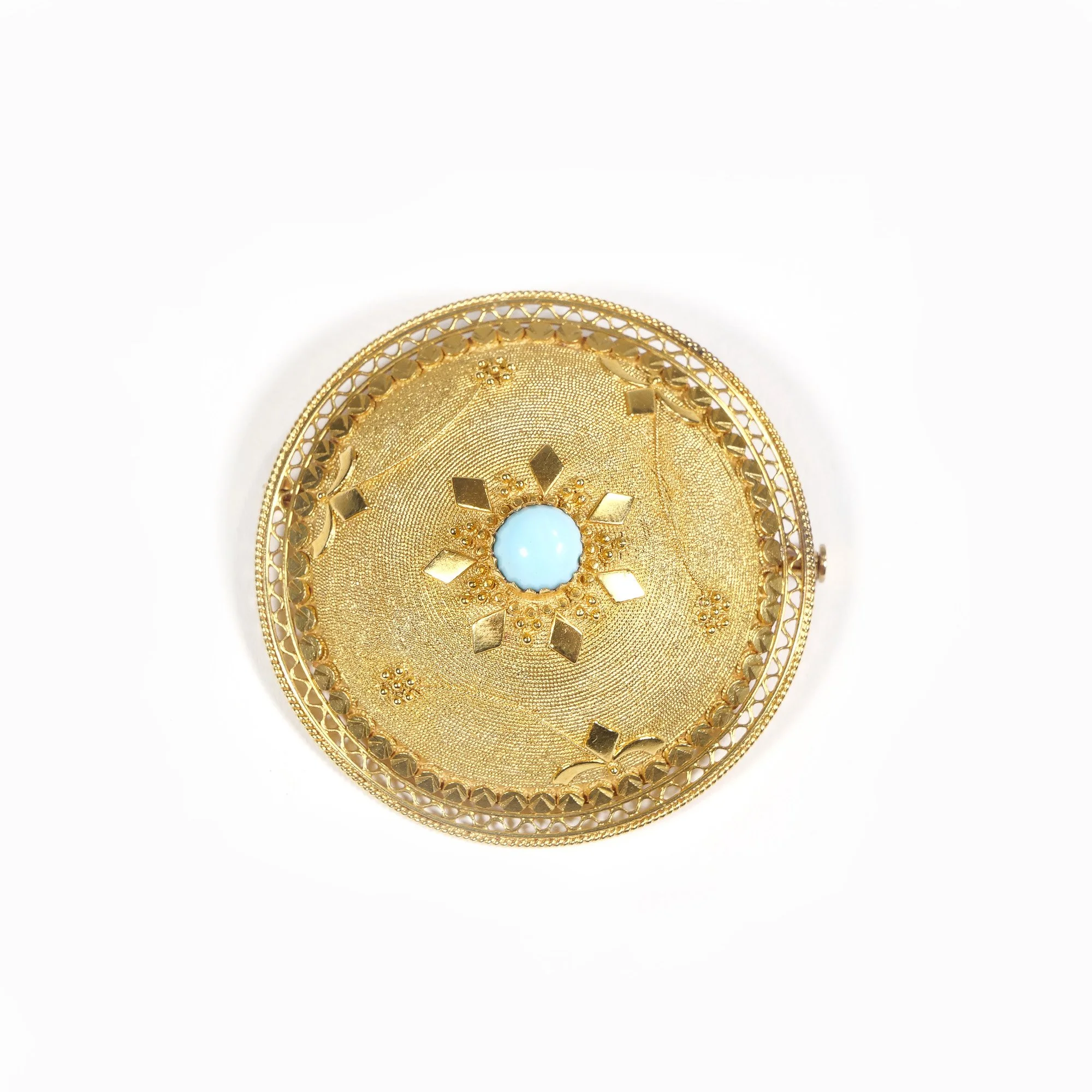 Elaborate gold brooch of round shape with intricate design, featuring a central light blue gemstone surrounded by gold petals and decorative patterns, auctioned and photographed by ACES Gallery.