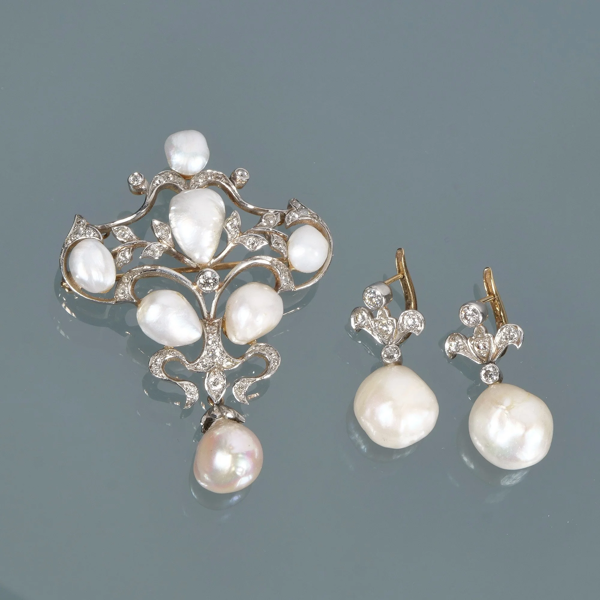 A matching set of jewelry including a brooch and a pair of earrings, all decorated with pearls and small diamonds, auctioned and photographed by ACES Gallery.