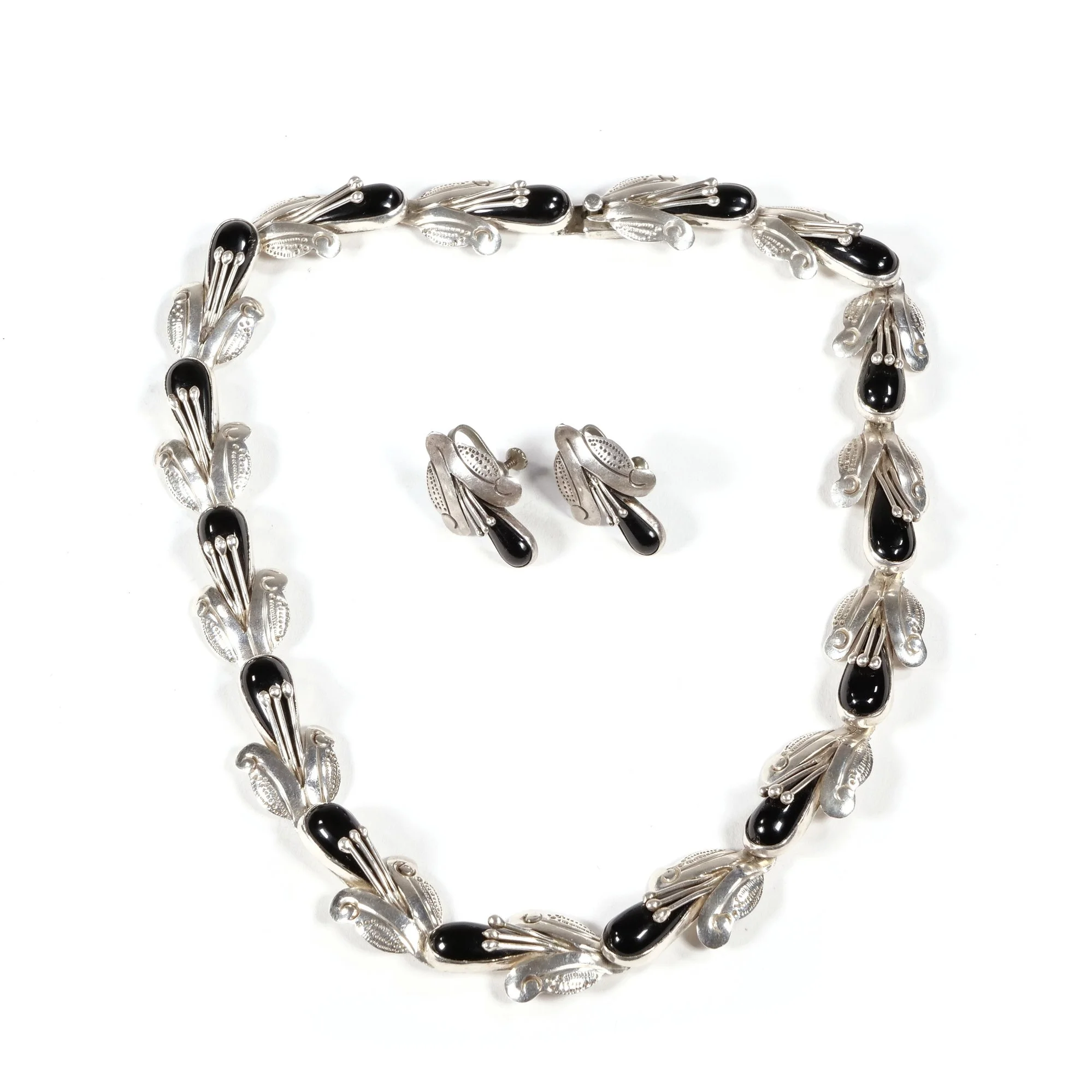 Silver jewelry set including a necklace and matching earrings with black and silver leaf-like design, auctioned and photographed by ACES Gallery.