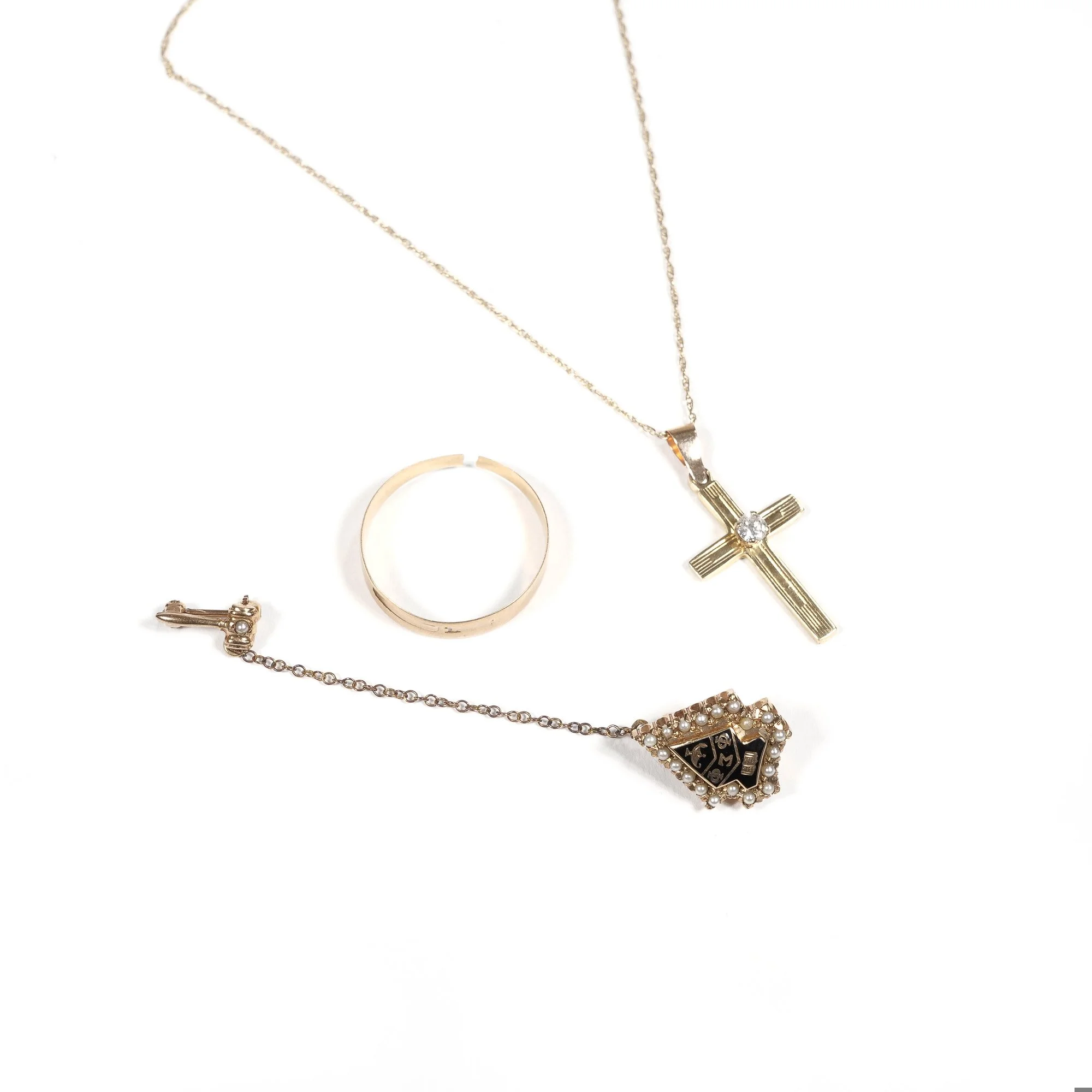 Gold cross pendant necklace, pearl-studded ring, gold band ring, and a pearl-embellished bracelet with a clock face design, auctioned and photographed by ACES Gallery.