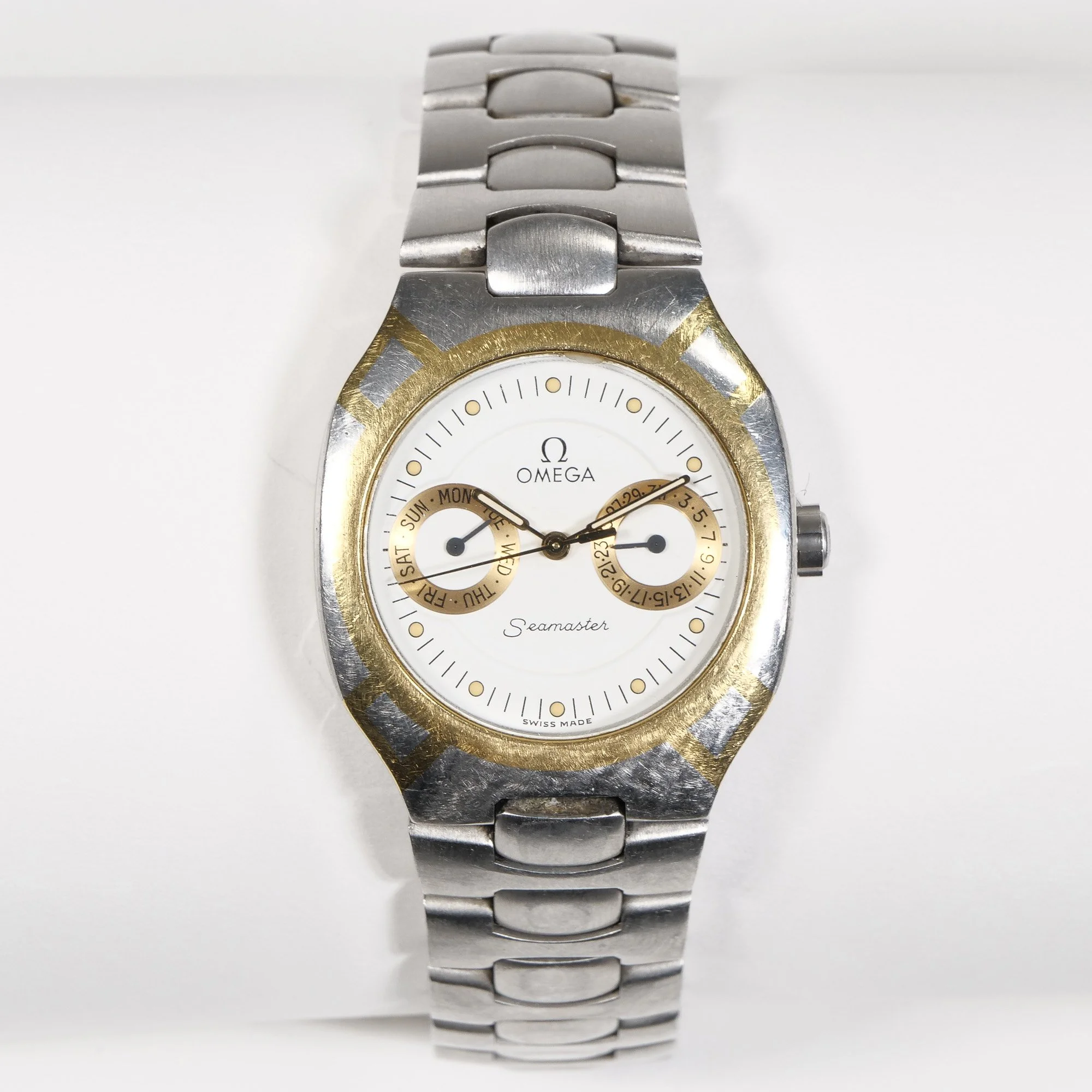 A men's Omega wristwatch with a white dial and gold accents, displaying the brand name, model Seamaster, with two subdials and gold markings, auctioned and photographed by ACES Gallery.