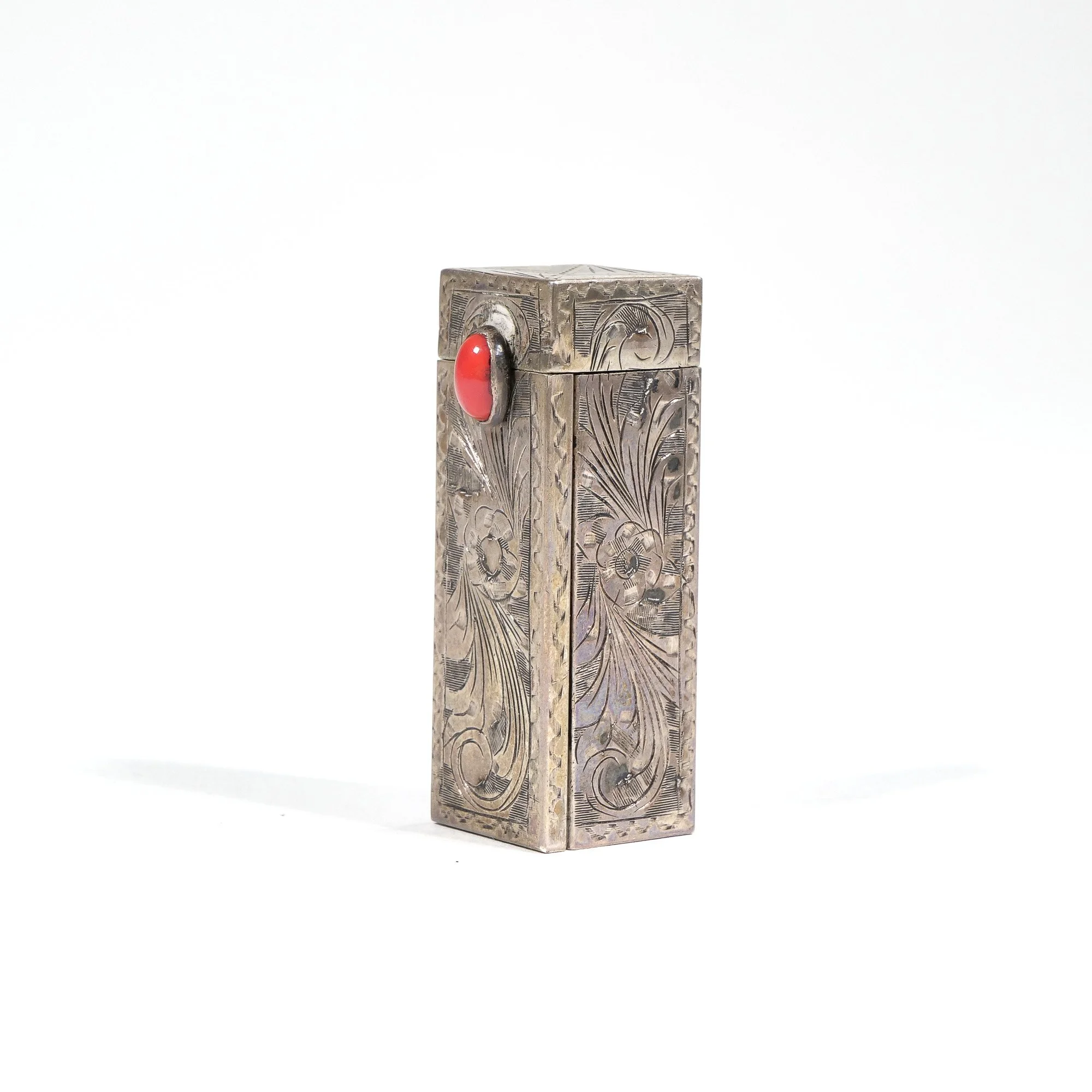 Sterling silver decorative lighter with floral engravings and a red button clasp, auctioned and photographed by ACES Gallery.