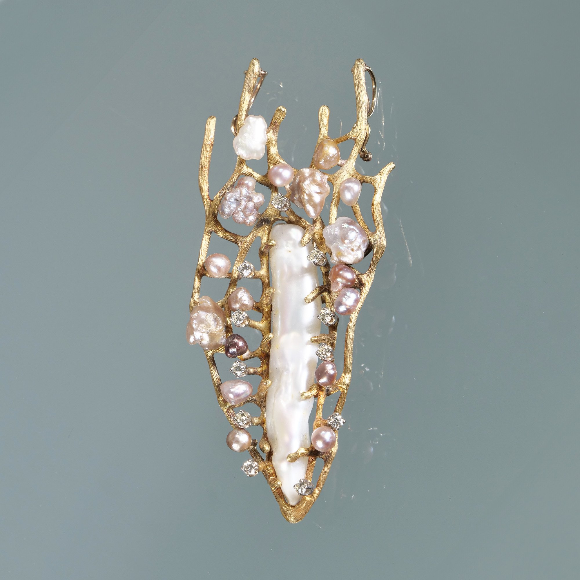 Gold brooch with pearls and diamonds surrounding a large baroque pearl on a plain background, auctioned and photographed by ACES Gallery.