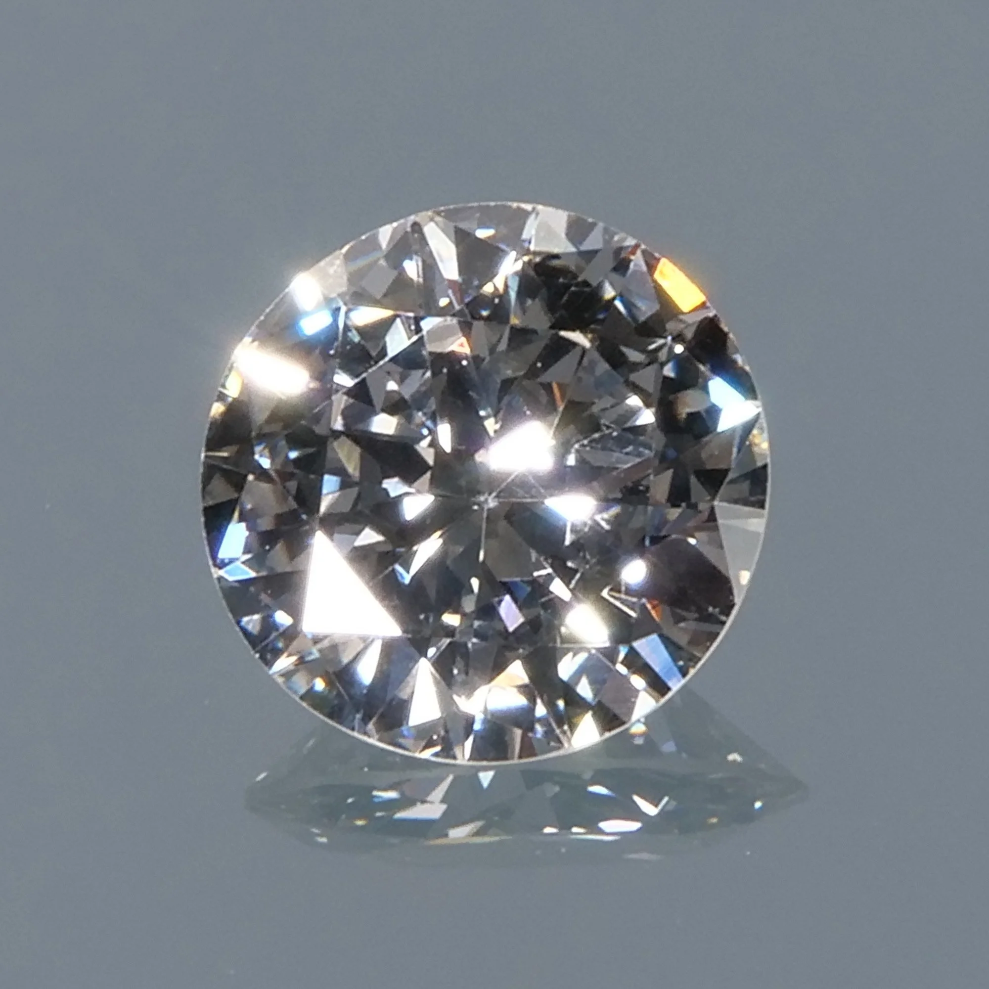 Close-up of a loose round brilliant-cut diamond on a reflective surface, auctioned and photographed by ACES Gallery.