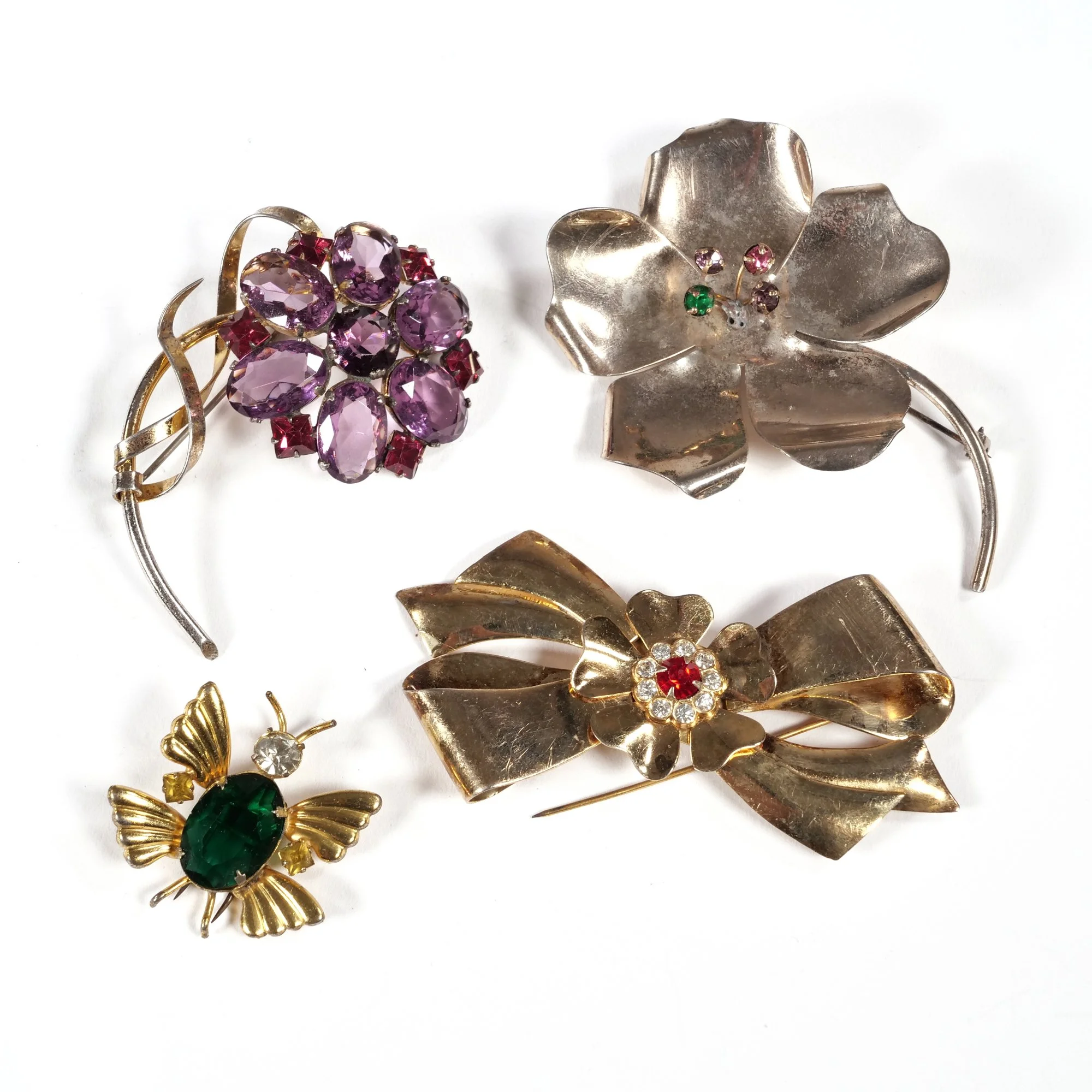 Collection of vintage brooches and pins with colorful gemstones and intricate designs on a white background, auctioned and photographed by ACES Gallery.
