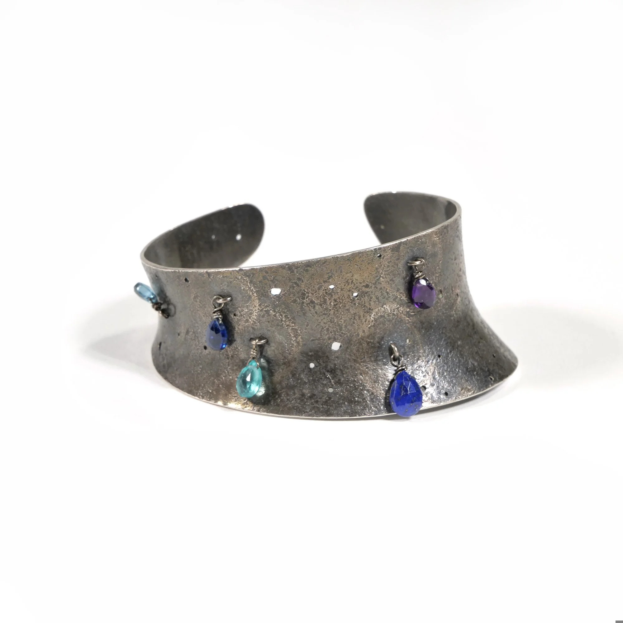 Vintage sterling silver cuff bracelet with five attached colorful gemstone charms on a white background, auctioned and photographed by ACES Gallery.