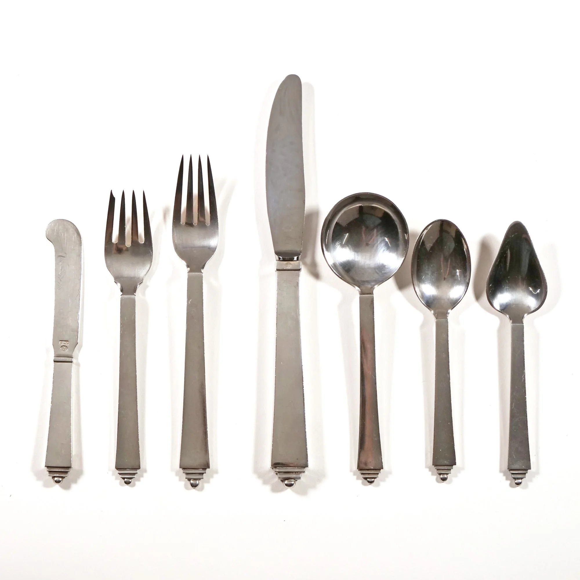 Set of six sterling silver utensils including a butter (or cheese) knife, two forks, a dinner knife, two spoons, and a teaspoon, arranged on a white background, auctioned and photographed by ACES Gallery.