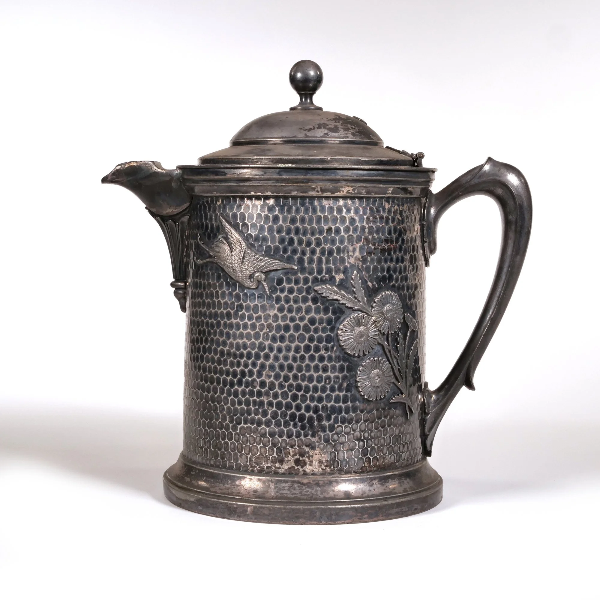 Vintage silverplated teapot with embossed floral and bird design, honeycomb pattern on surface, rounded lid, and curved handle, auctioned and photographed by ACES Gallery.