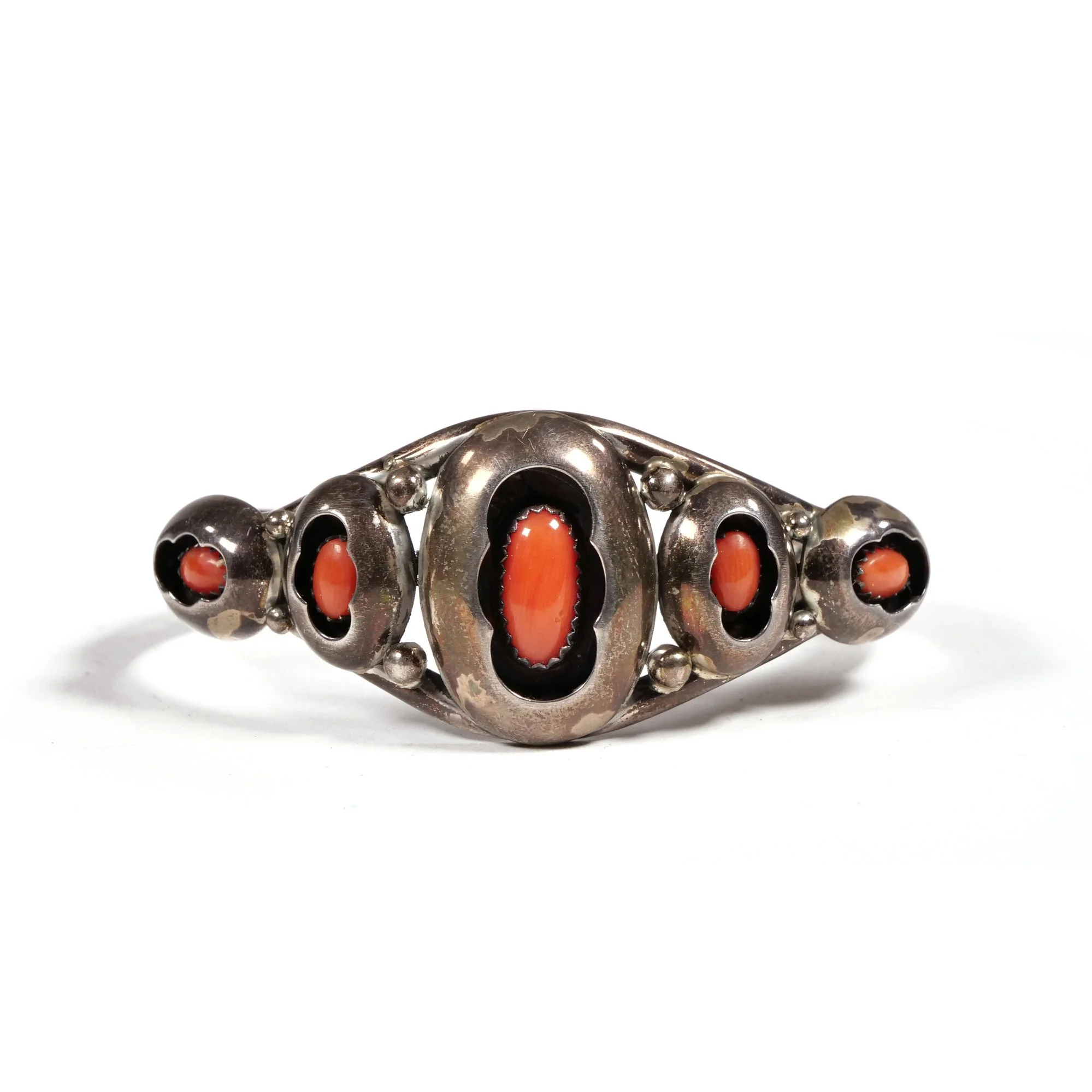 Silver ring with five oval coral stones, set in decorative bezels, arranged in a linear pattern, auctioned and photographed by ACES Gallery.