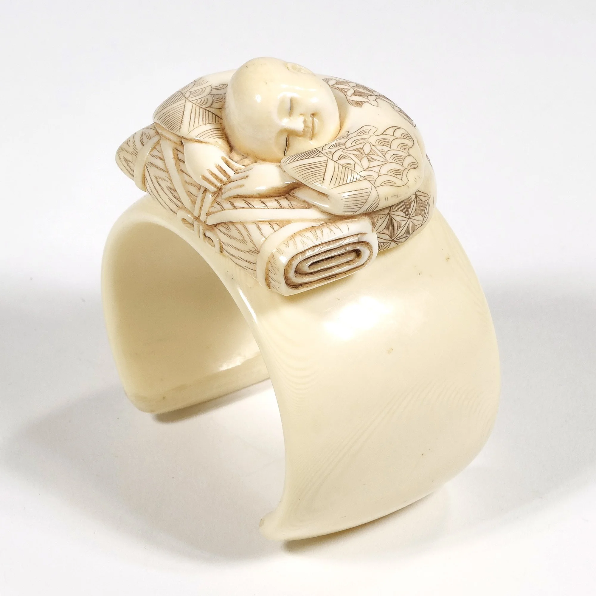 Cream-colored ring with a carved woman sleeping on a pillow resting her head on her arms, auctioned and photographed by ACES Gallery.