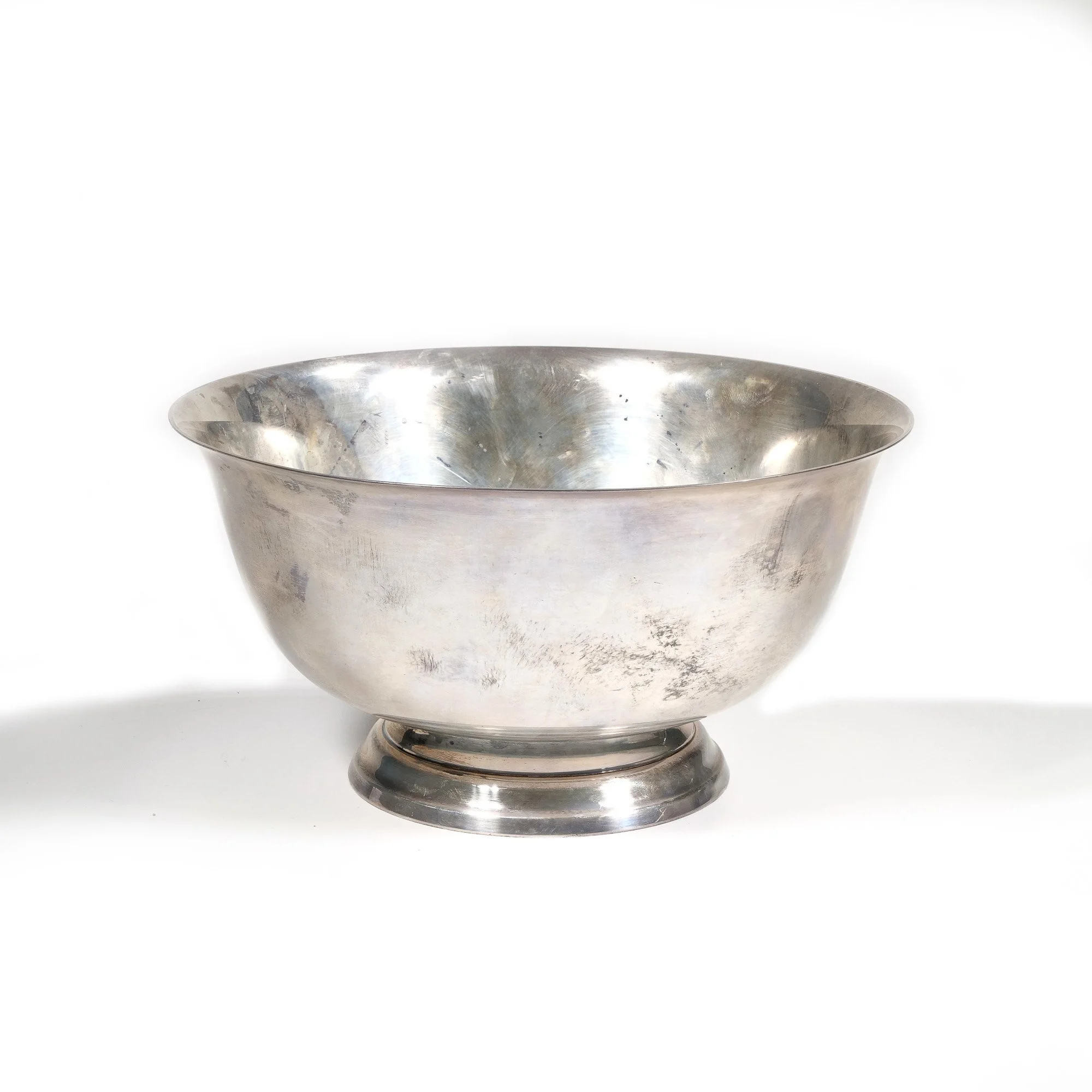 A silver bowl with a slightly tarnished surface, resting on a circular base, auctioned and photographed by ACES Gallery.