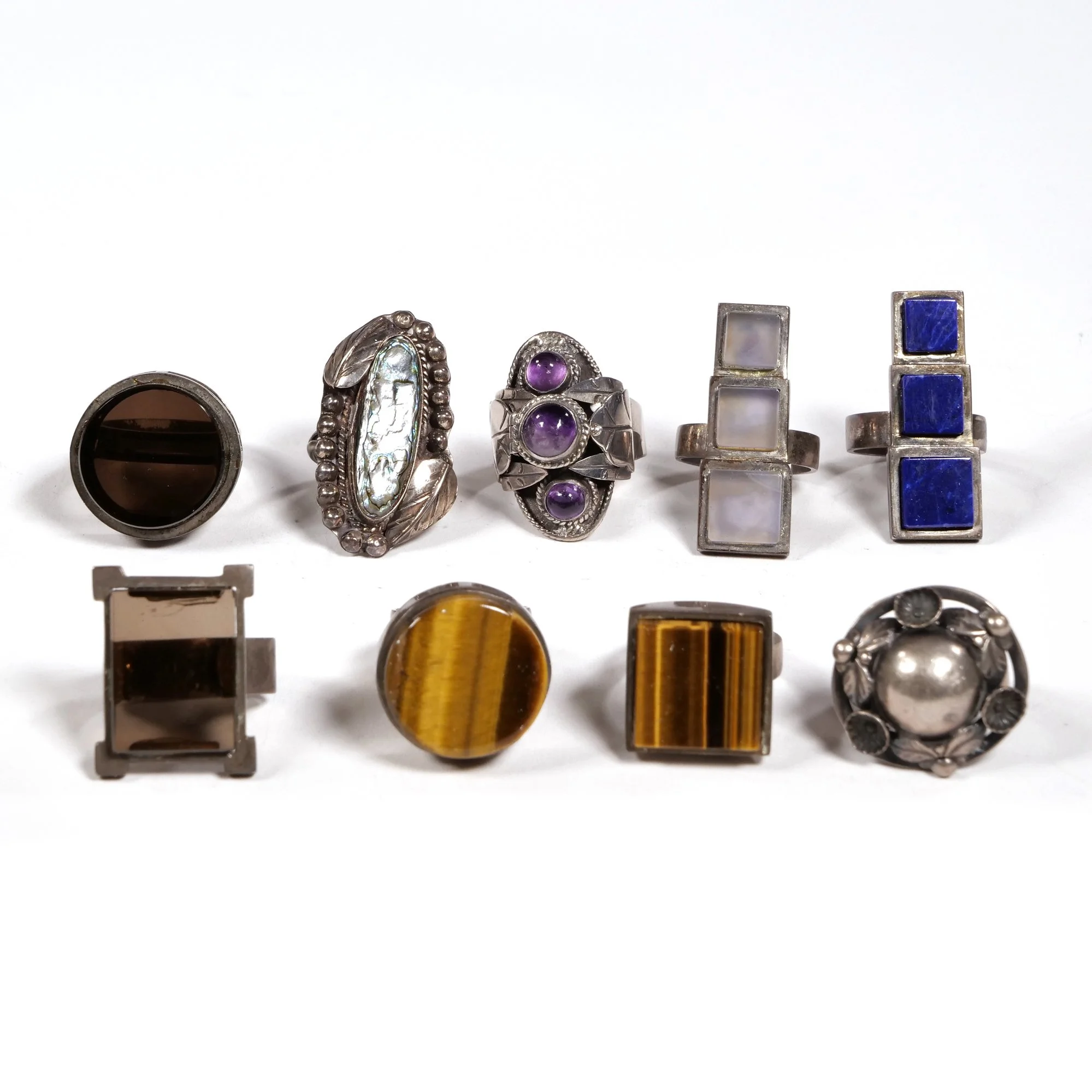 Collection of ten vintage rings with various gemstones and designs on a white background, auctioned and photographed by ACES Gallery.