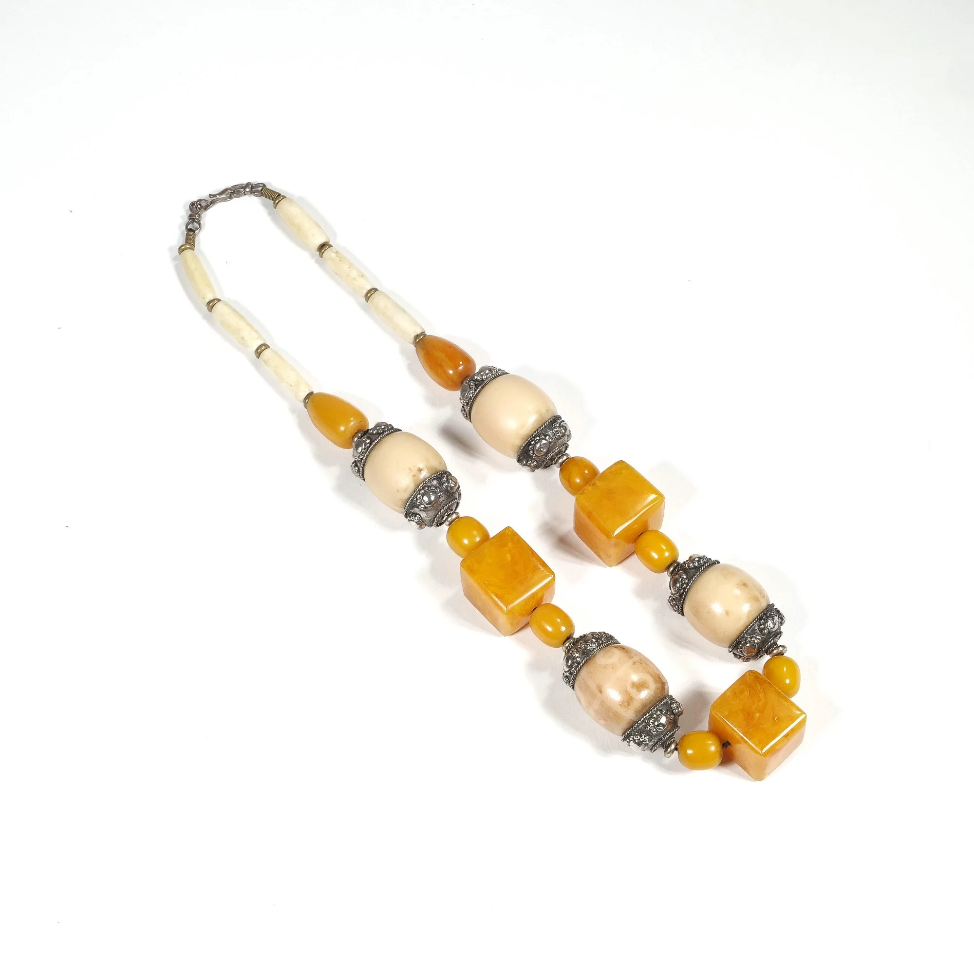 Beaded necklace with white, yellow, and amber-colored beads arranged in a pattern, set against a plain white background, auctioned and photographed by ACES Gallery.