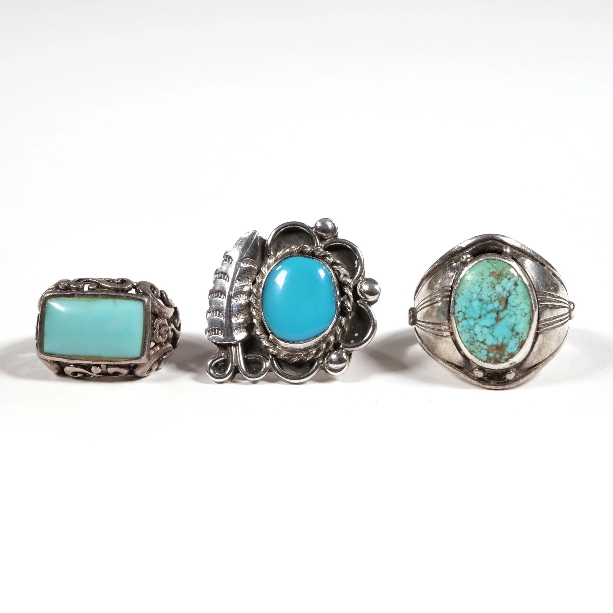 Three silver rings with turquoise stones, displayed in a row, auctioned and photographed by ACES Gallery.