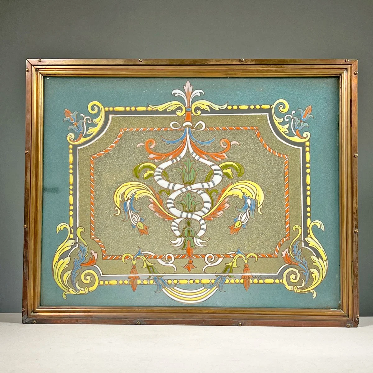 Decorative framed artwork with intricate floral and scroll patterns in yellow, green, orange, blue, and white on a green background, auctioned and photographed by ACES Gallery.