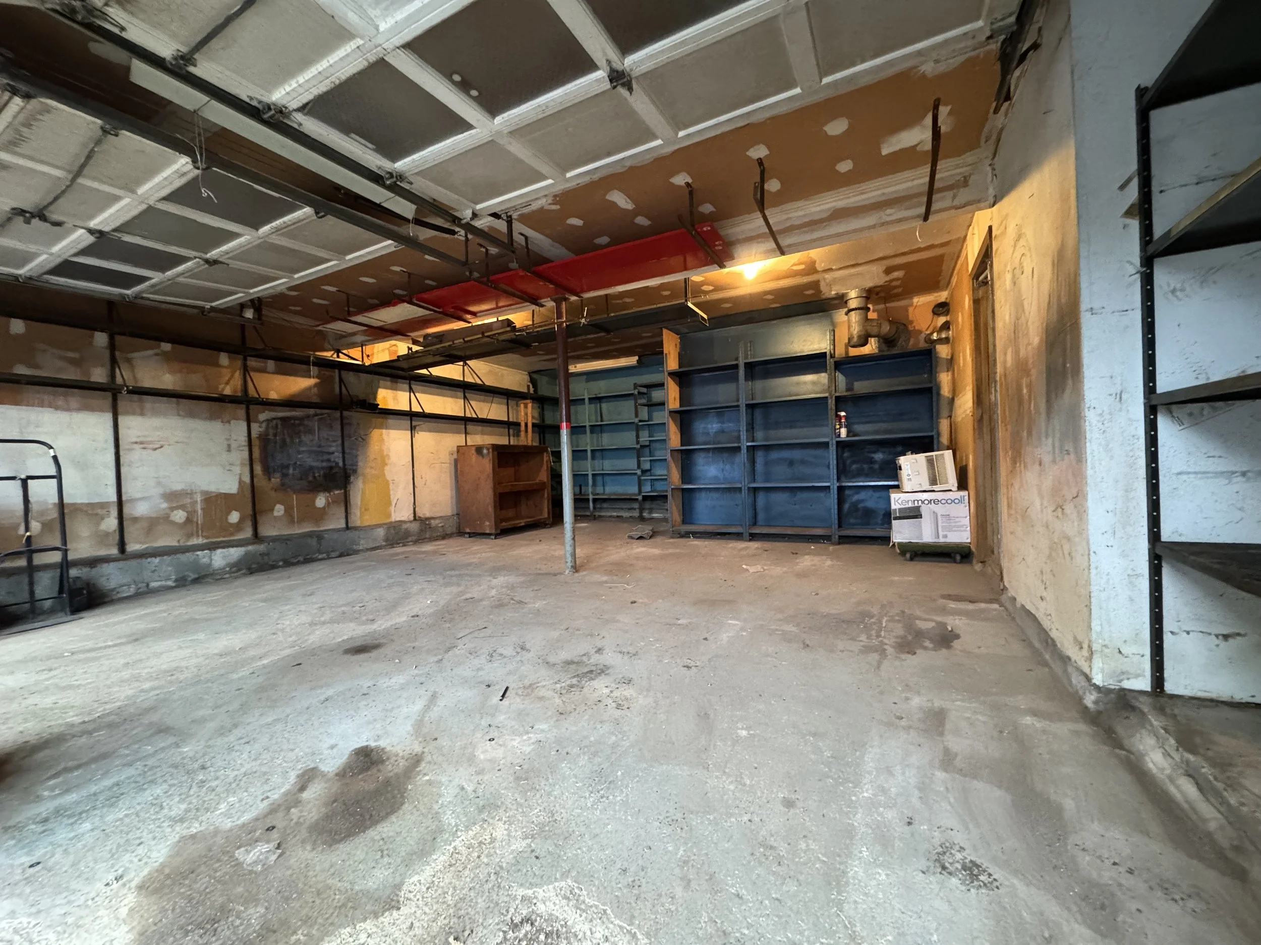 Empty garage with unfinished walls, concrete flooring, and empty shelves, cleared and photographed by ACES.