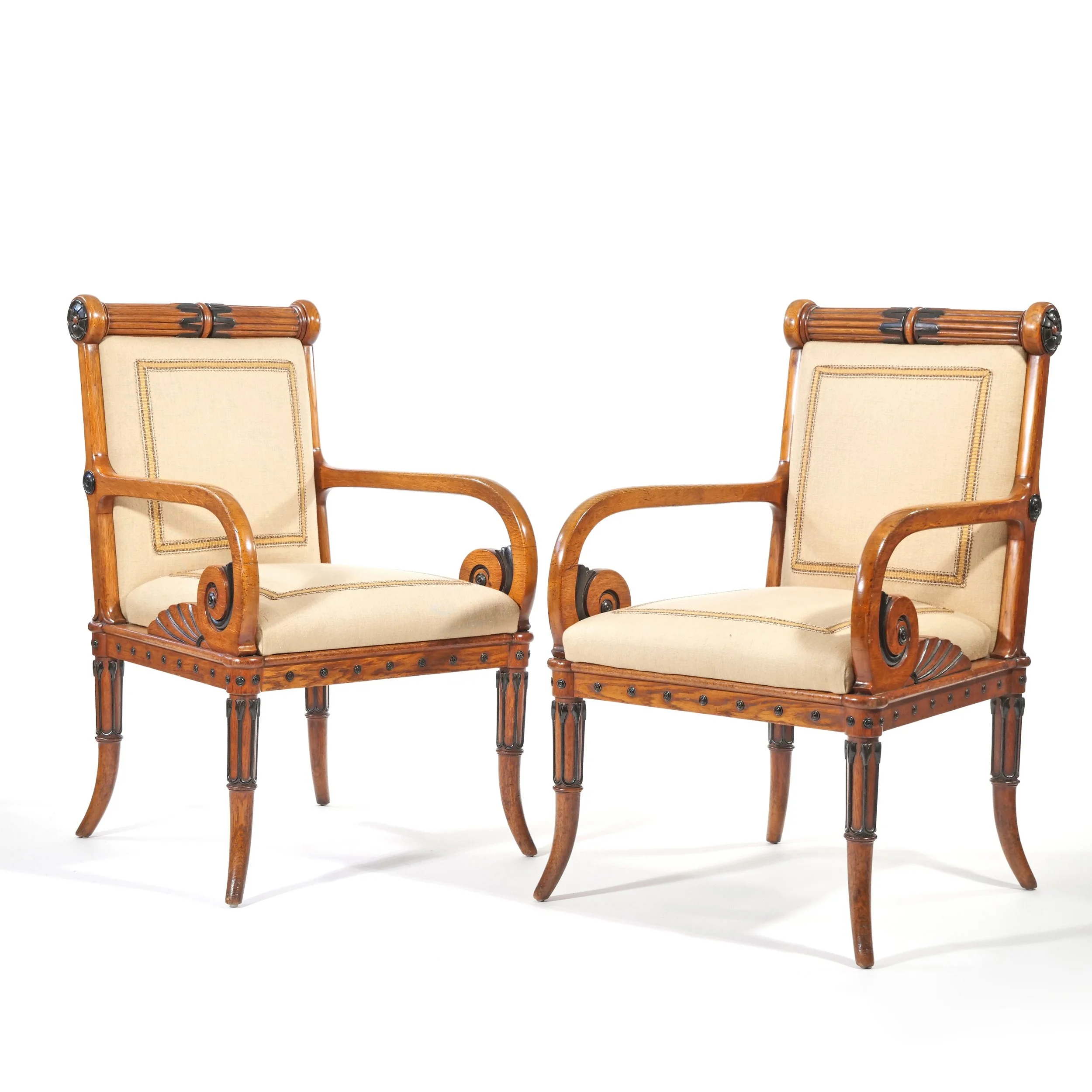 Two vintage wooden armchairs with beige cushions and carved details.