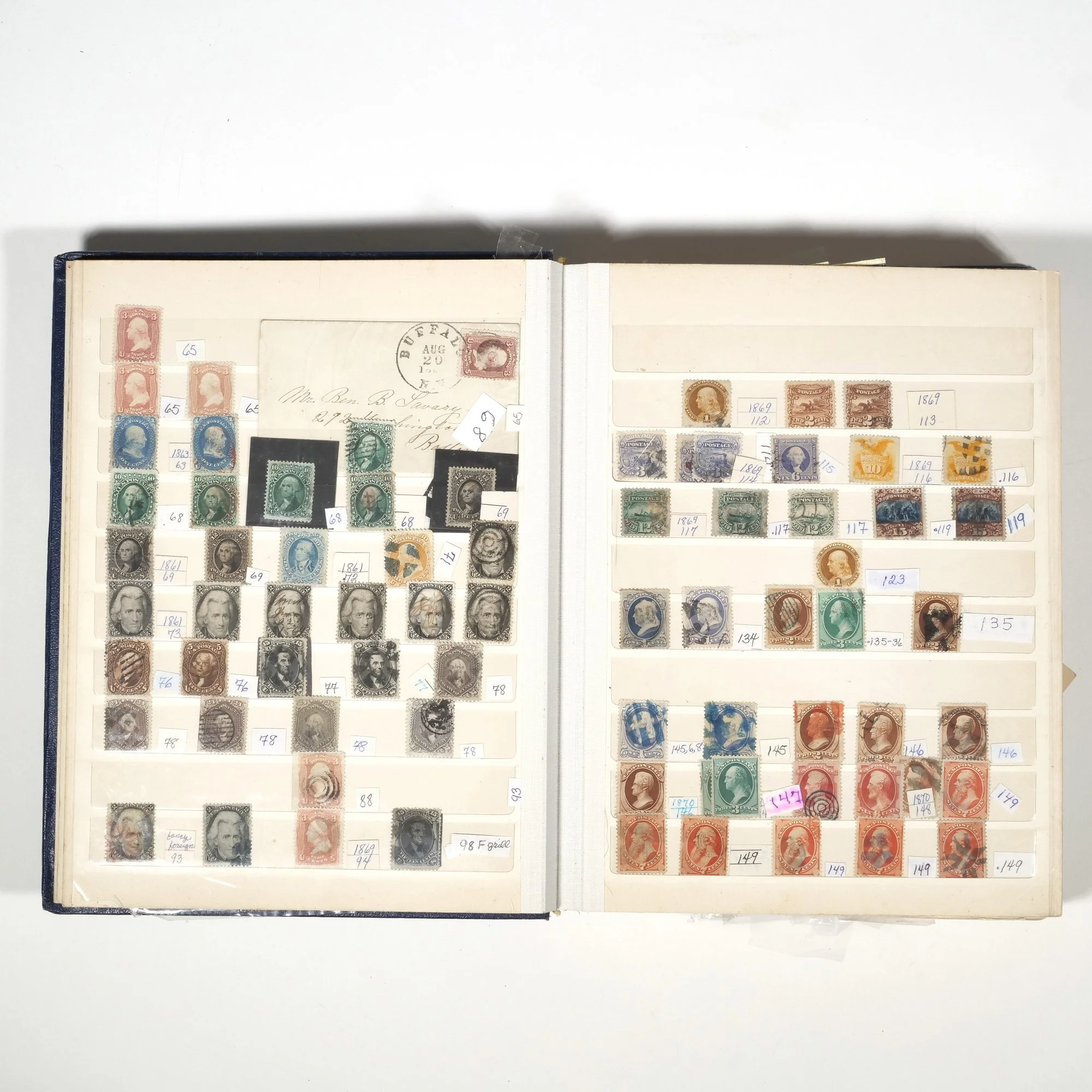 A stamp collection in an album with various vintage stamps organized on pages, some with handwritten labels and annotations, auctioned and photographed by ACES Gallery.