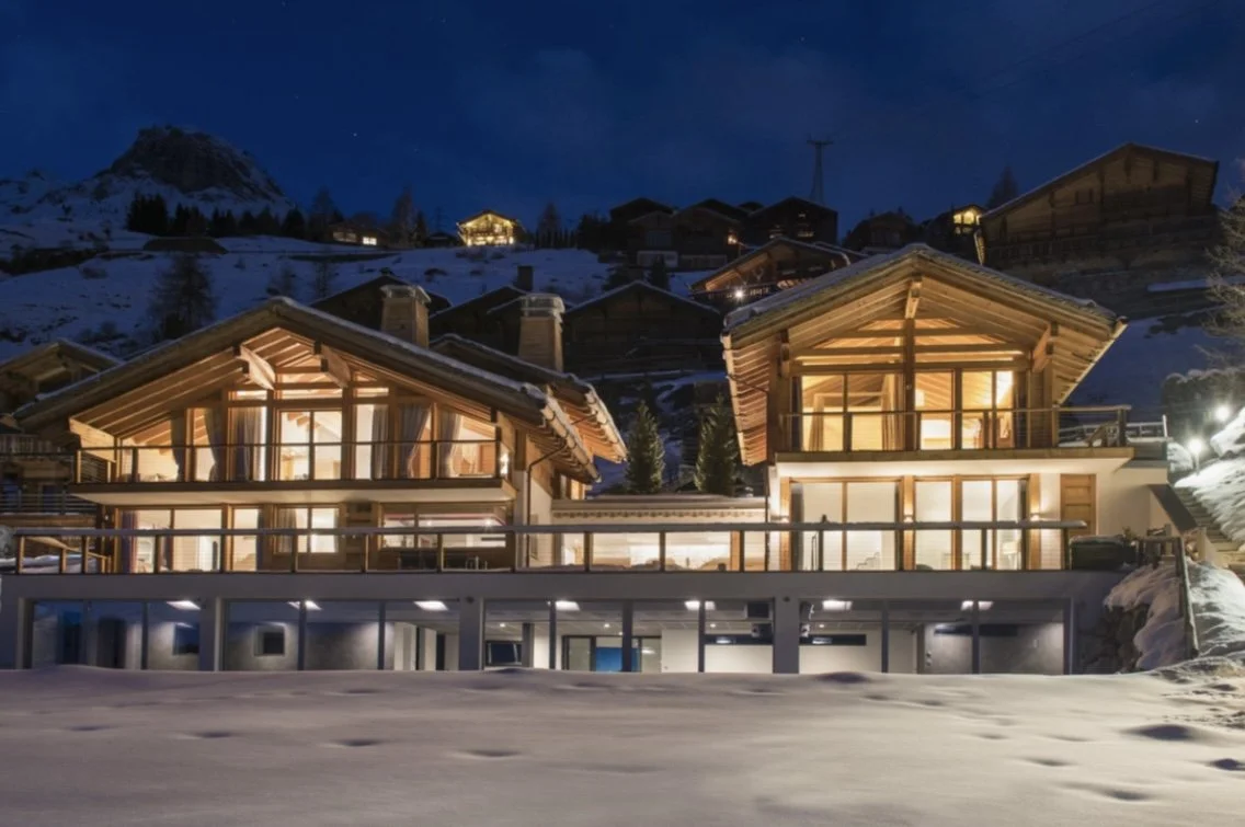 Scenic landscape of mountains, a lake, and rolling grassy hills with sparse trees.