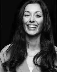 A smiling woman with long dark hair in black and white.