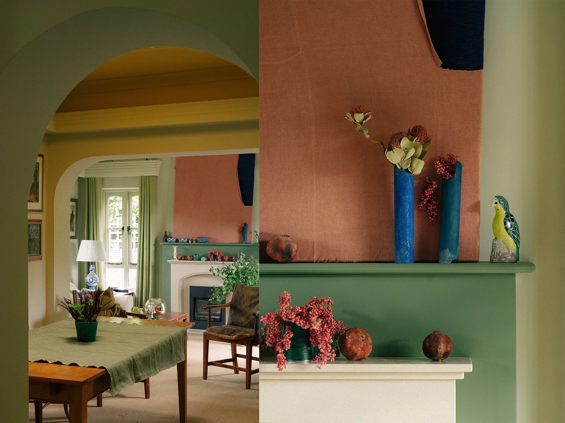 Interior of a cozy room with a dining table, chairs, a fireplace, and a seating area near windows with green curtains, decorated with plants and flowers.