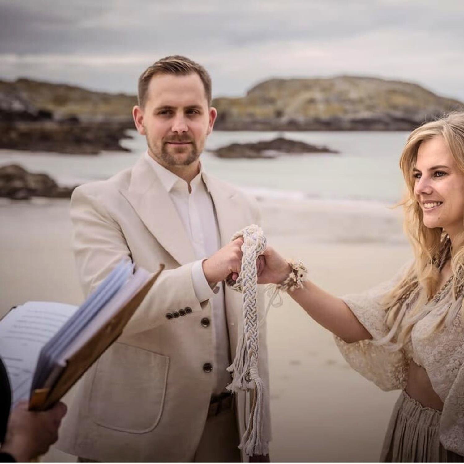 Ein Brautpaar bei der rechtsgültigen Trauung in Schottland am Strand beim Handfasting