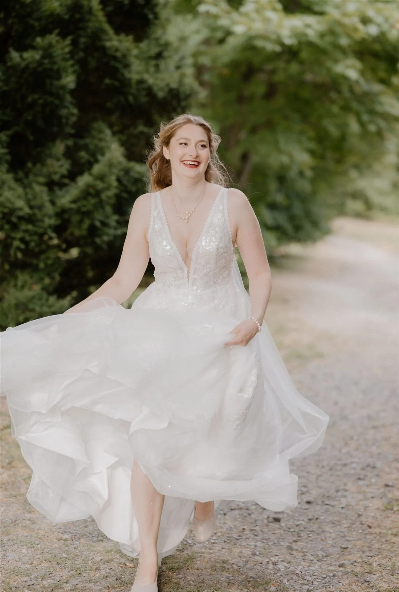 Braut rennt lachend mit wehendem Kleid im sanften Gegenlicht