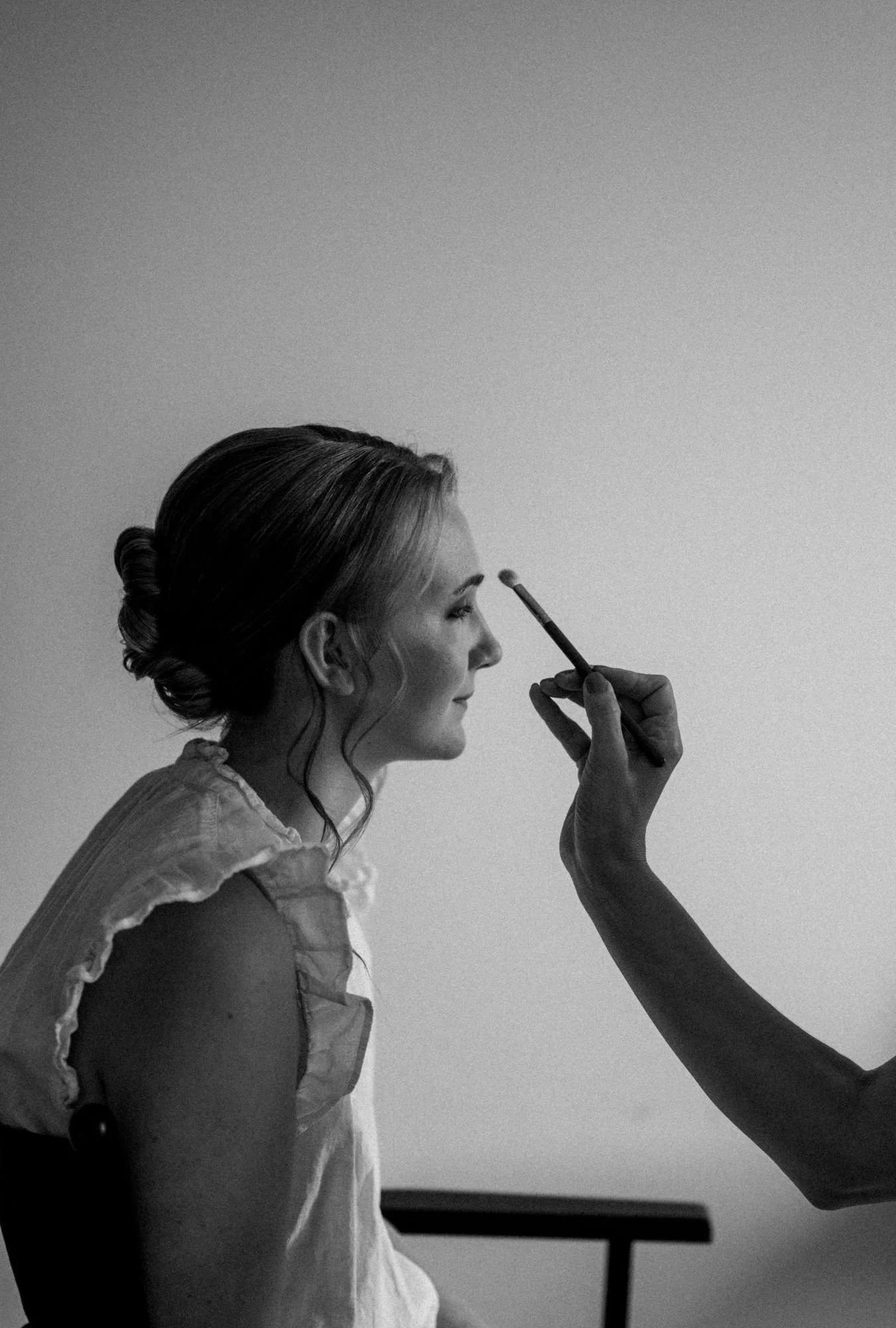 Braut beim Getting Ready mit Brautstylistin die Pinsel in der Hand hält