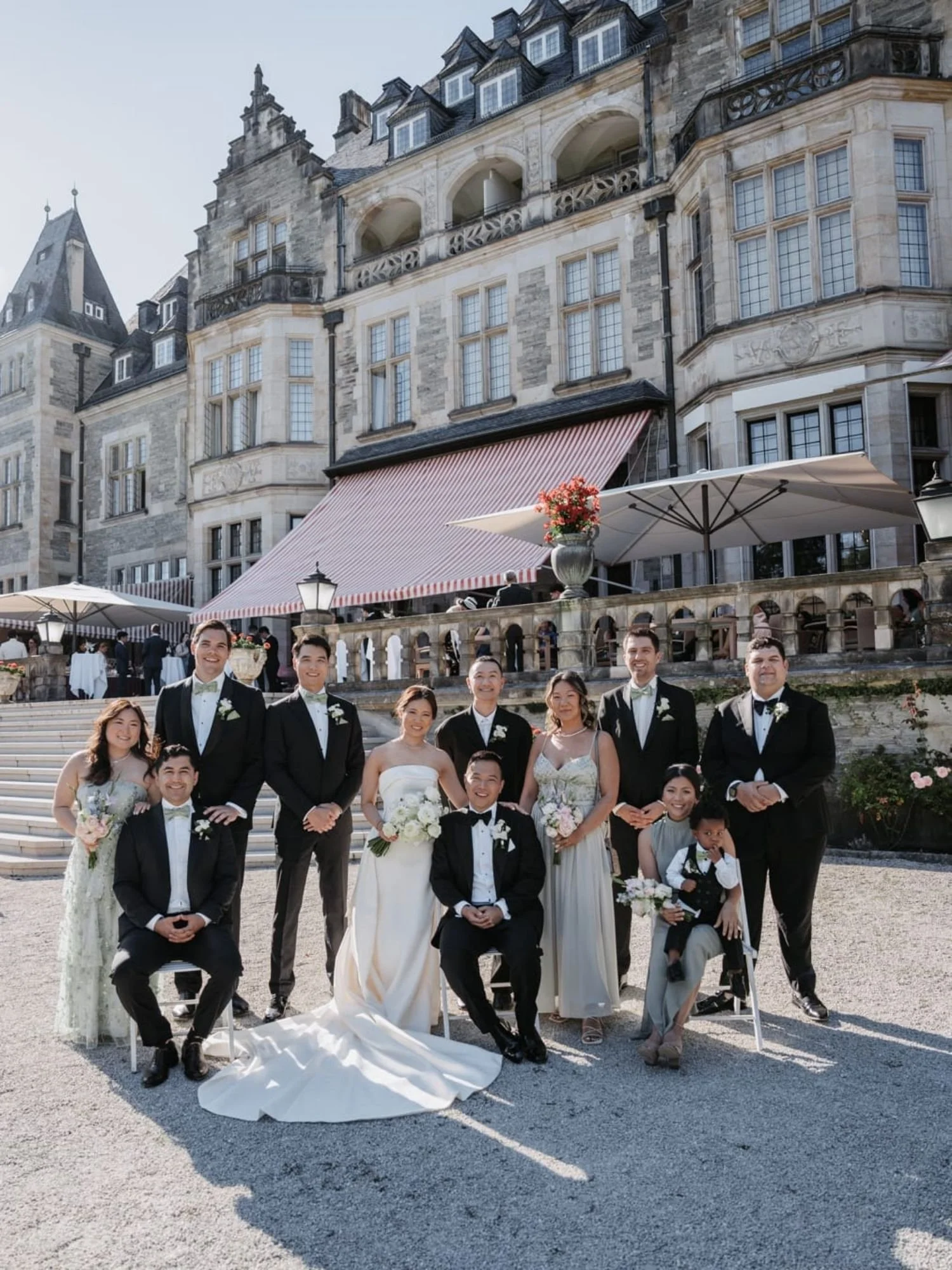 Brautpaar und Hochzeitsgäste in stilvollem historischen Ambiente vor einem Schloss