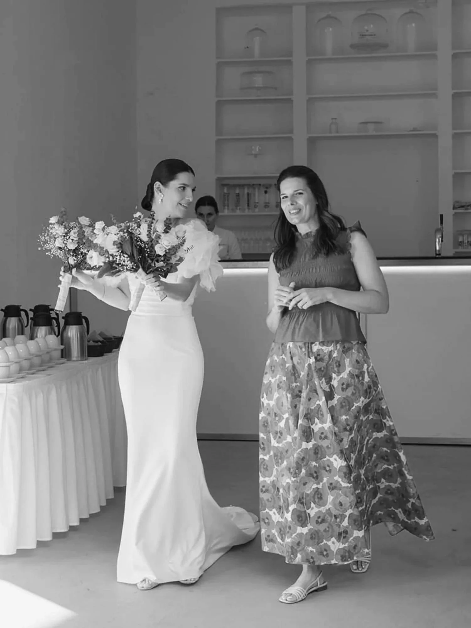 Hochzeitsplanerin und Braut gehen gemeinsam und lächeln sich an.