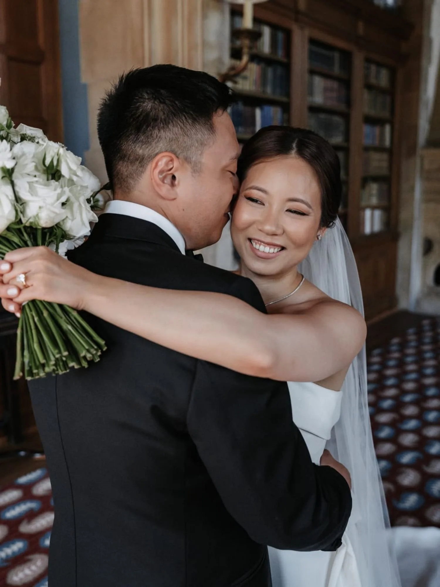 Glückliches Brautpaar im Moment der Umarmung mit Soft Glam Styling der Braut