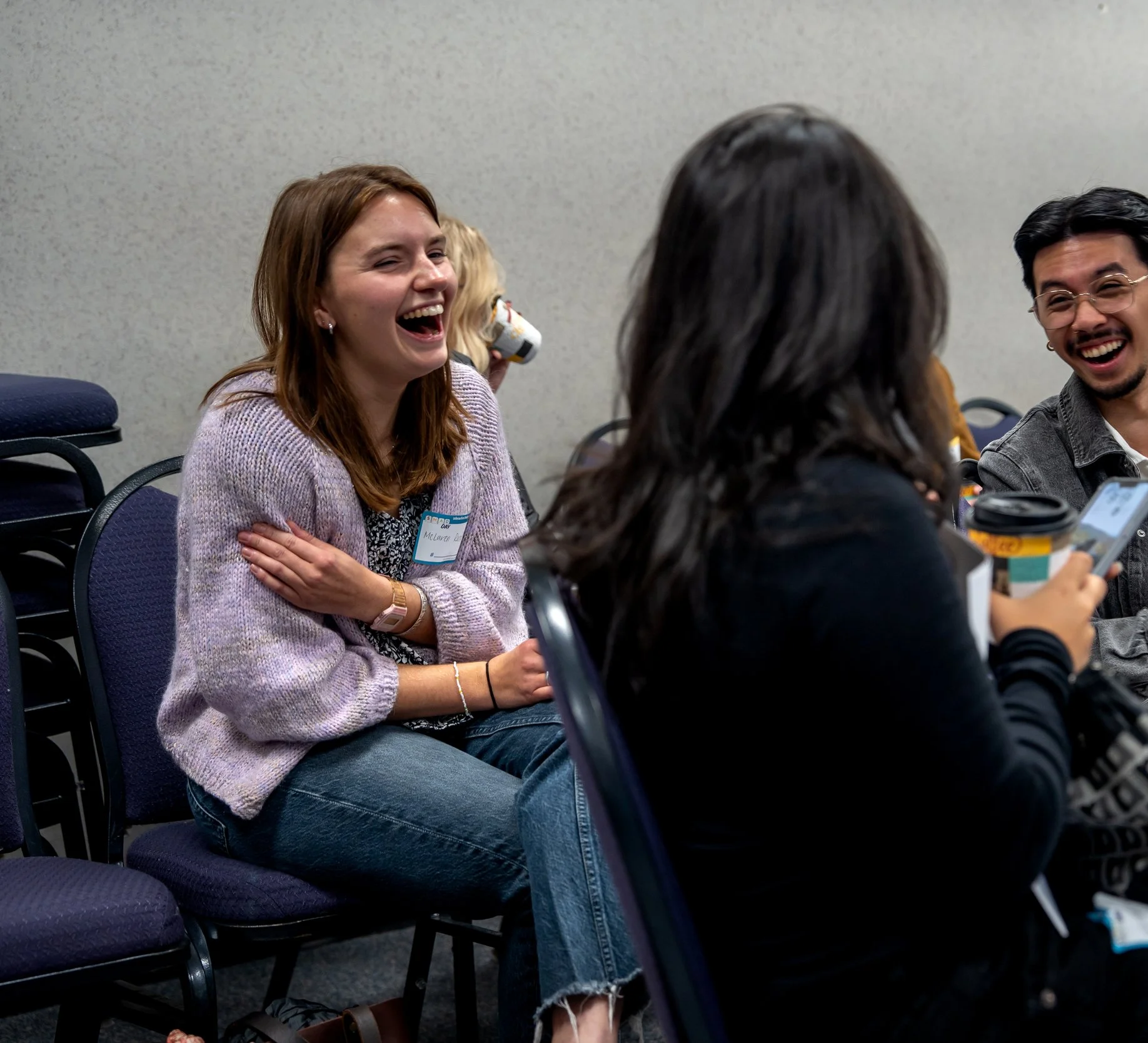 Group of four diverse young adults sitting and laughing at a JMU SMAD Event
