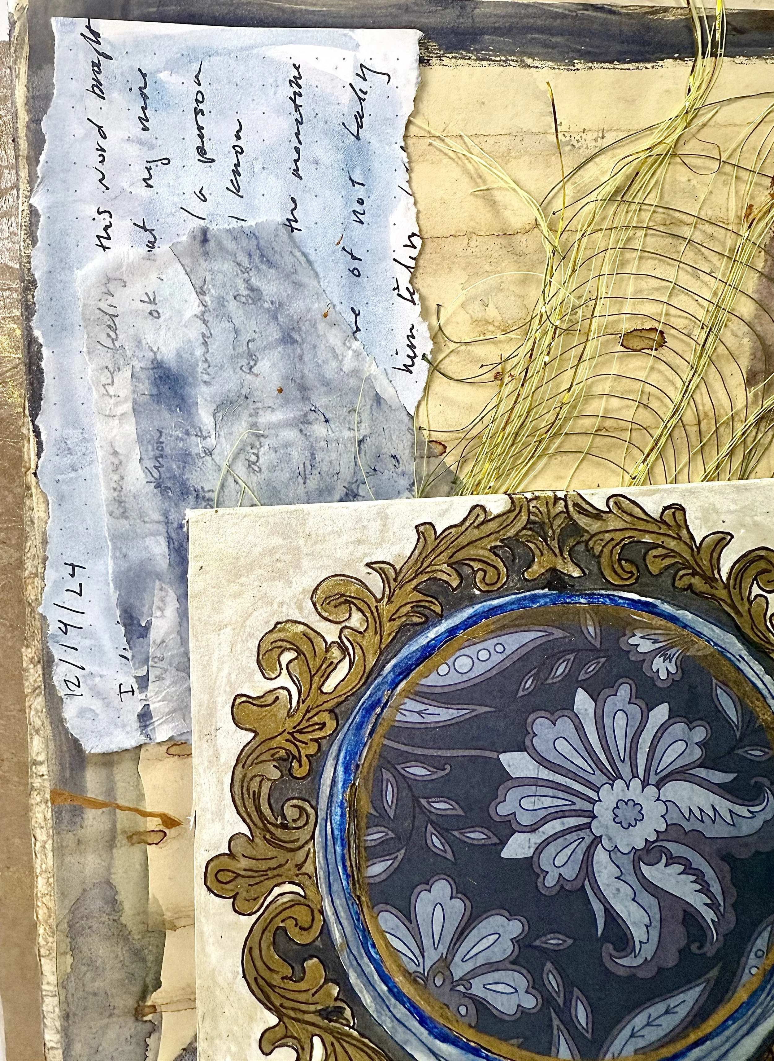 A torn handwritten note, a decorative framed artwork, and dried grass on a piece of cardboard.