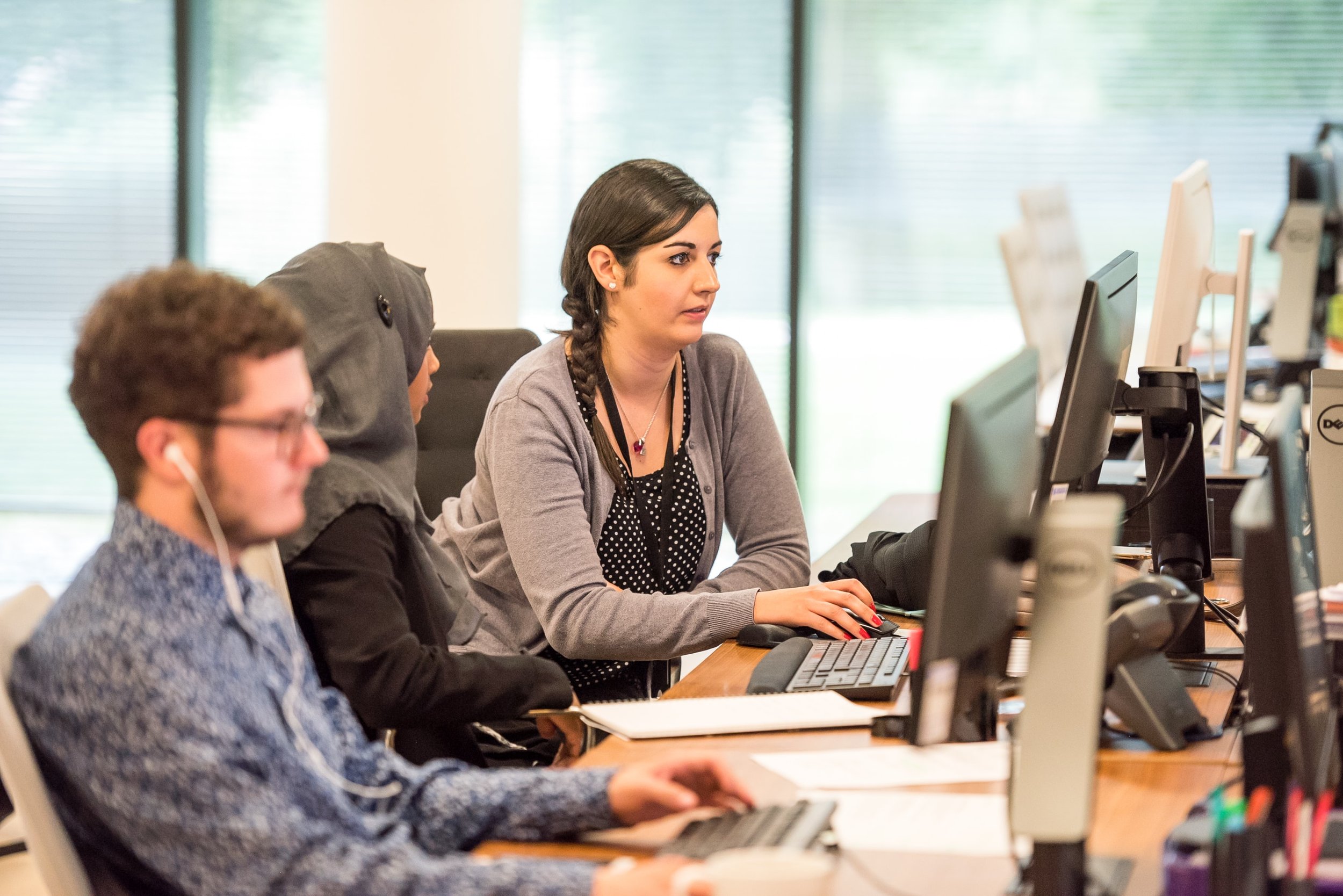 Employees working at desks with computers in an office.
