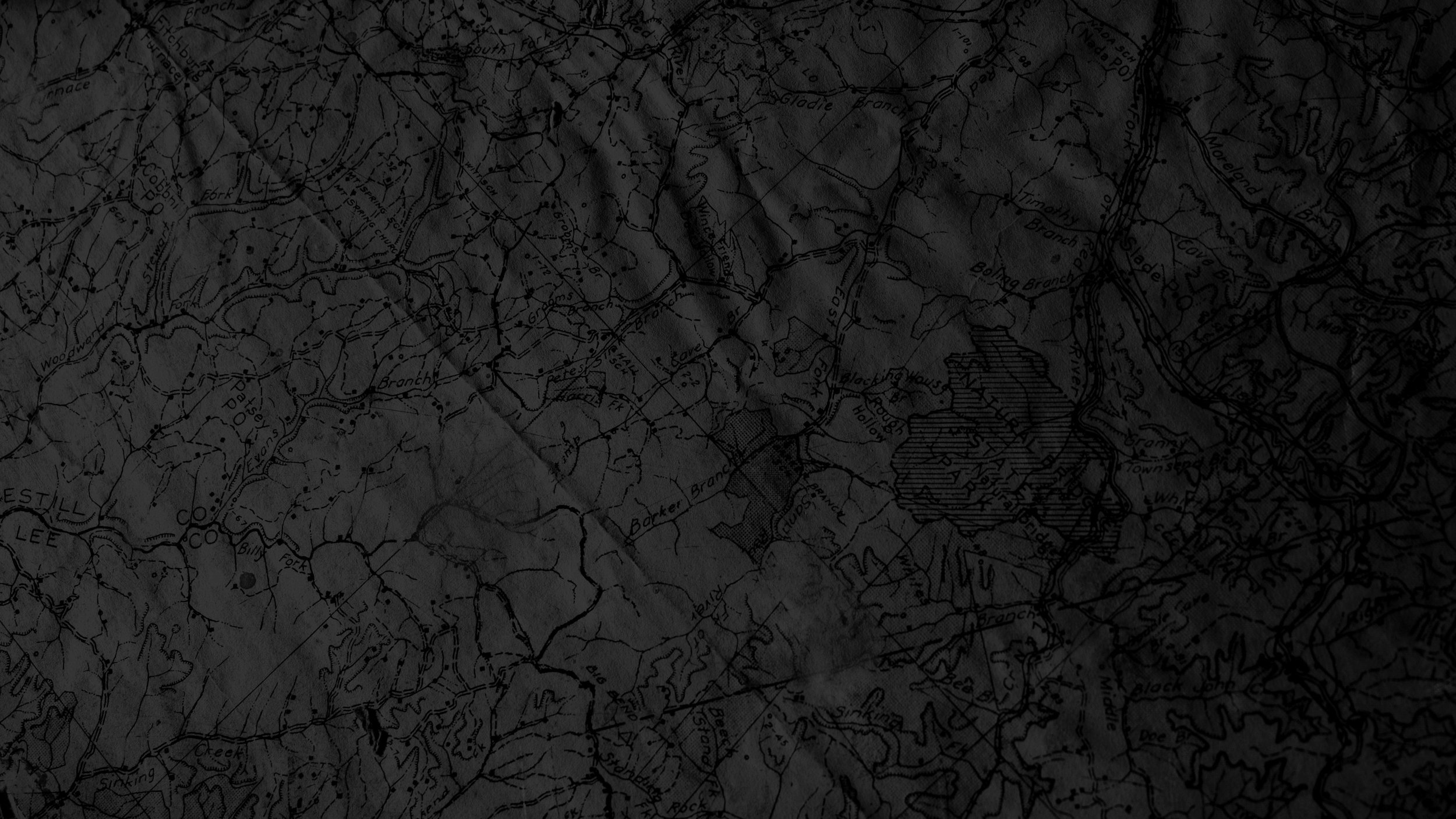 A dark, crumpled map showing topographical details and place names.