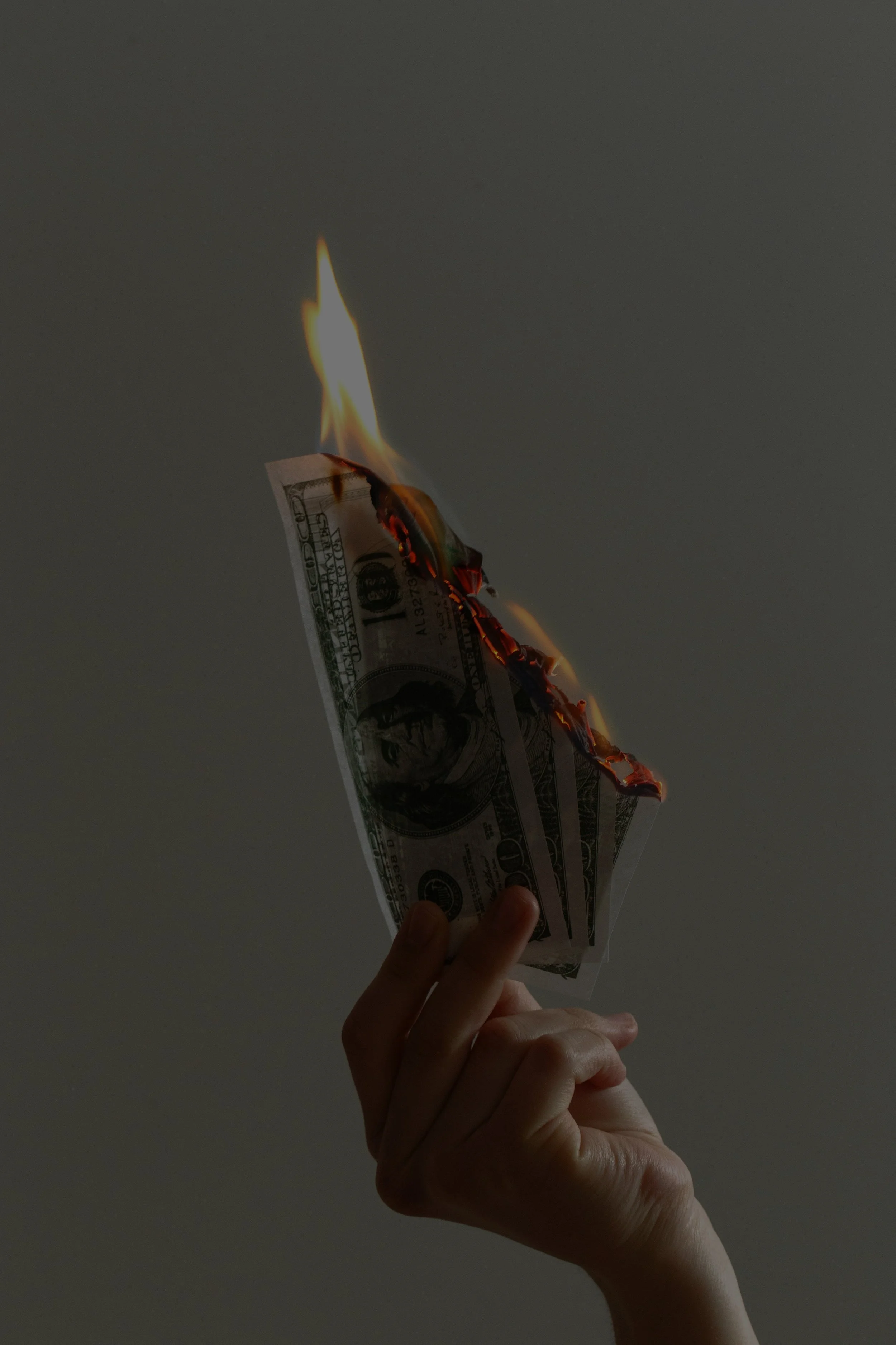 Hand holding burning $100 bill.
